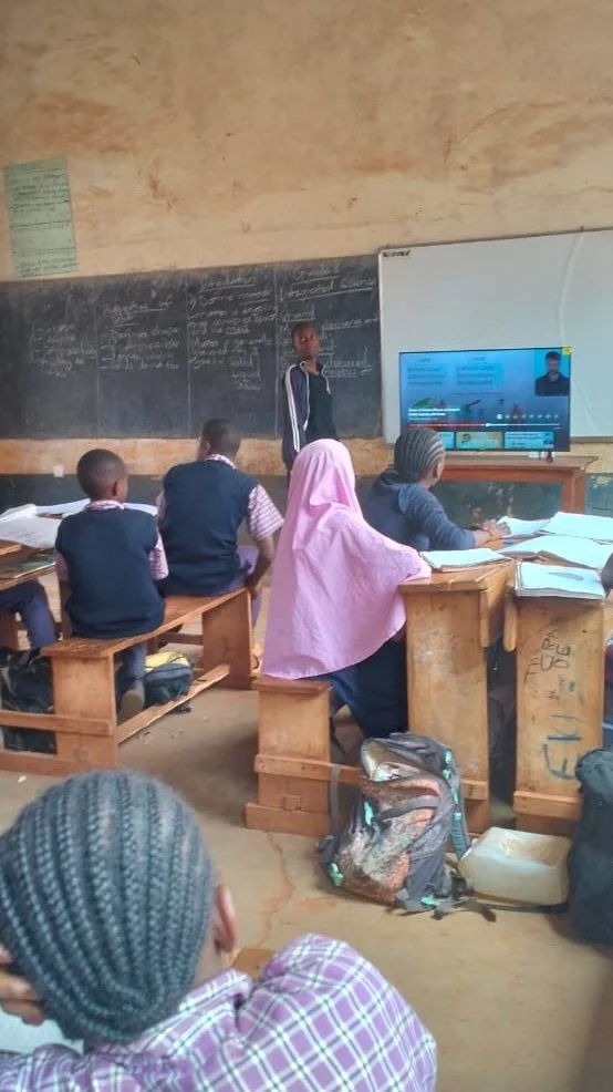 image of a classroom of students in Kenya watching a young student present to the class