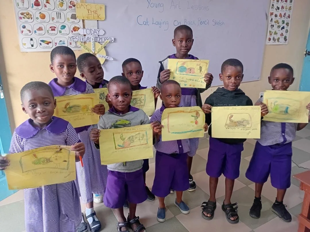 image of a group of ghanan students holding up their artwork and smiling at the camera