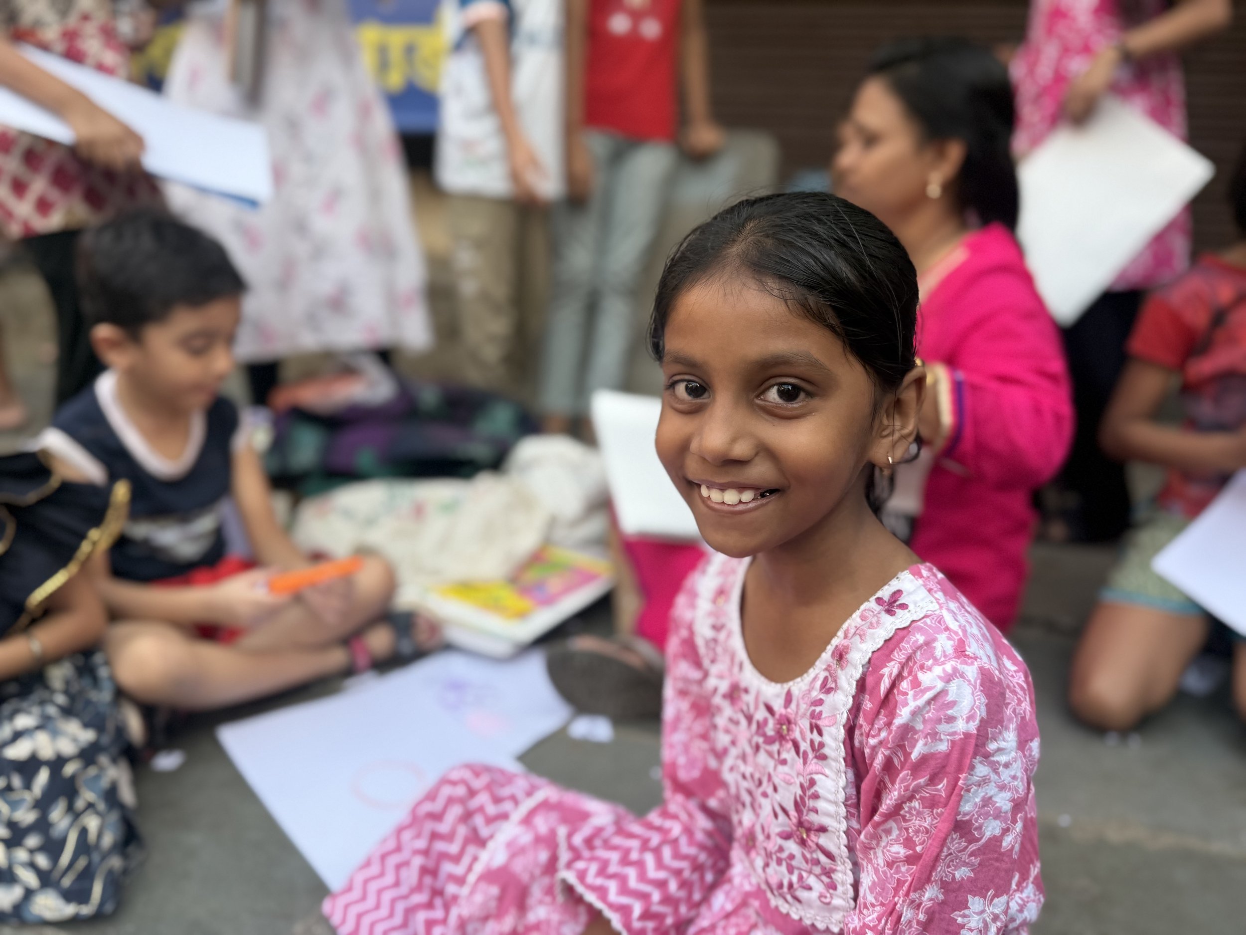 image of a young girl in india sitting on the ground and smiling at the camera