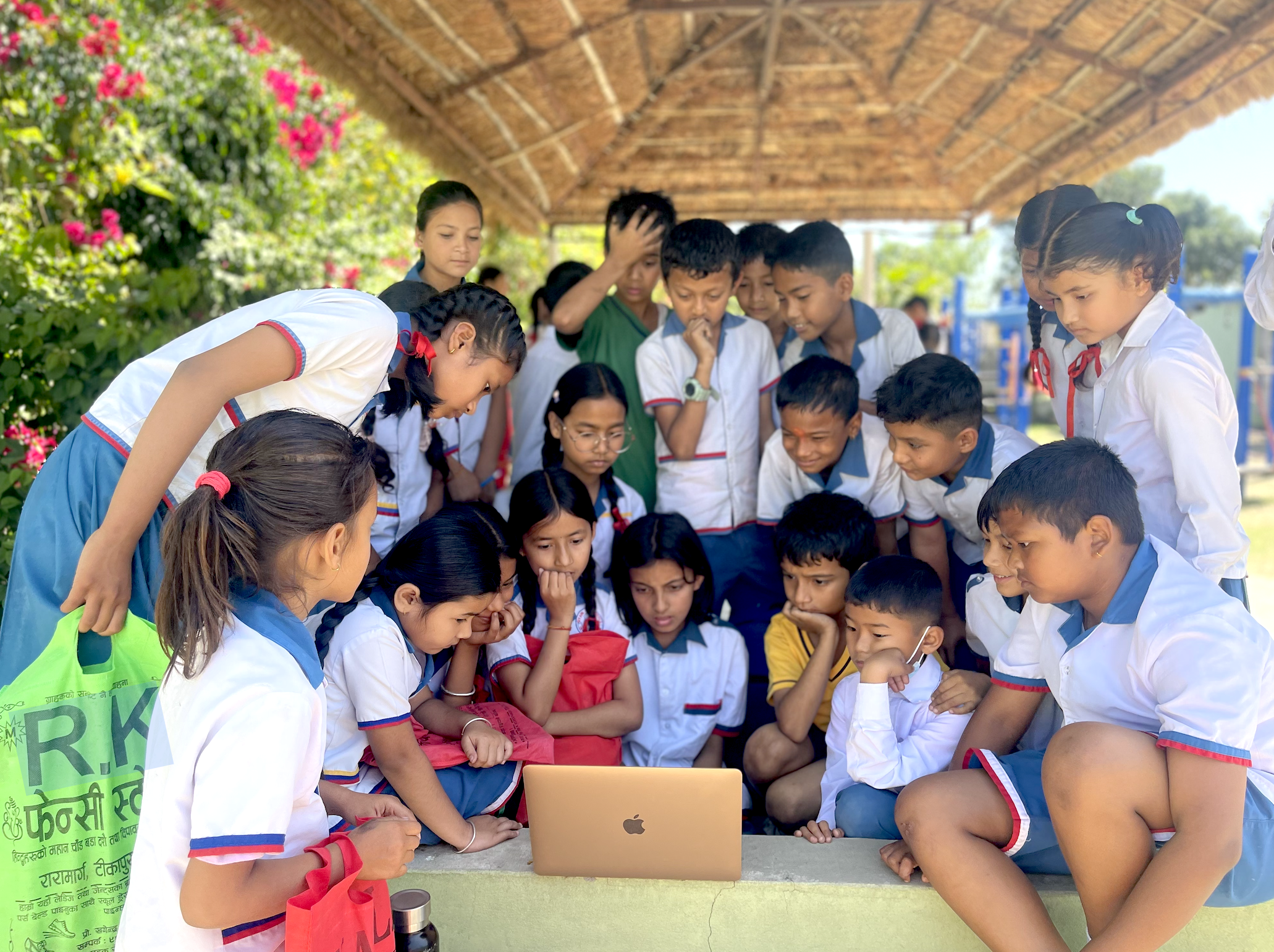 a large group of students huddled around a laptop outside