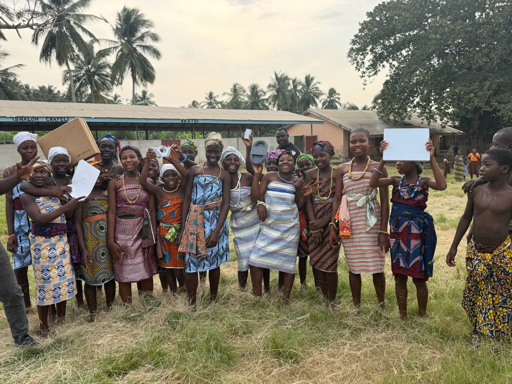 a group of african students satnding in a line and smiling while holding up starlinks