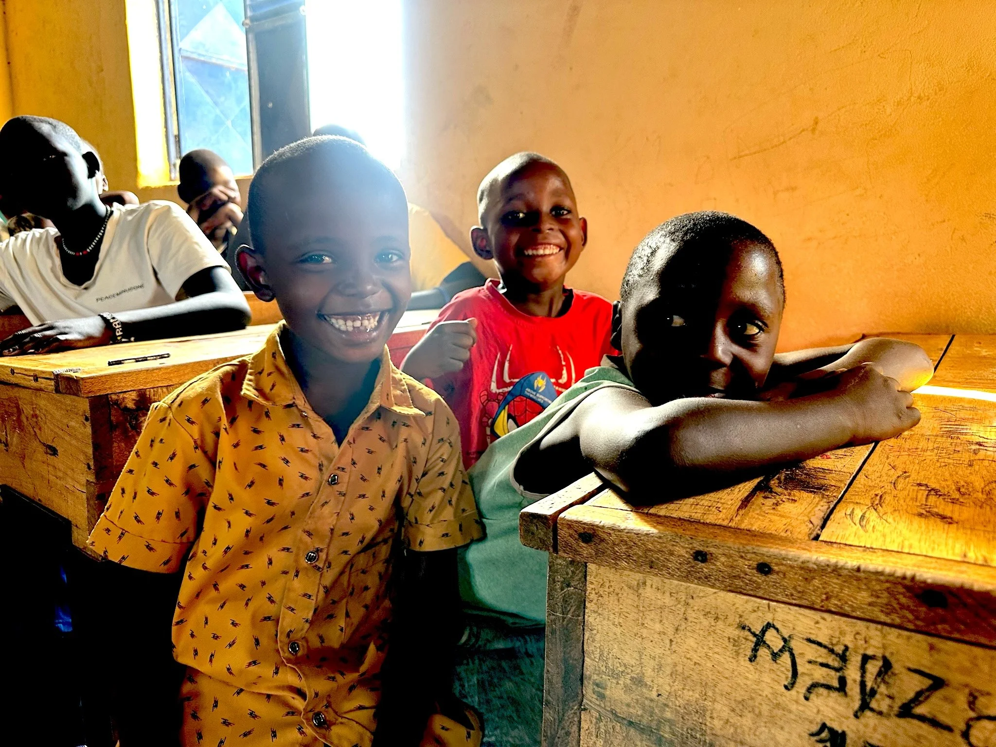 three boys sitting at school desks smiling