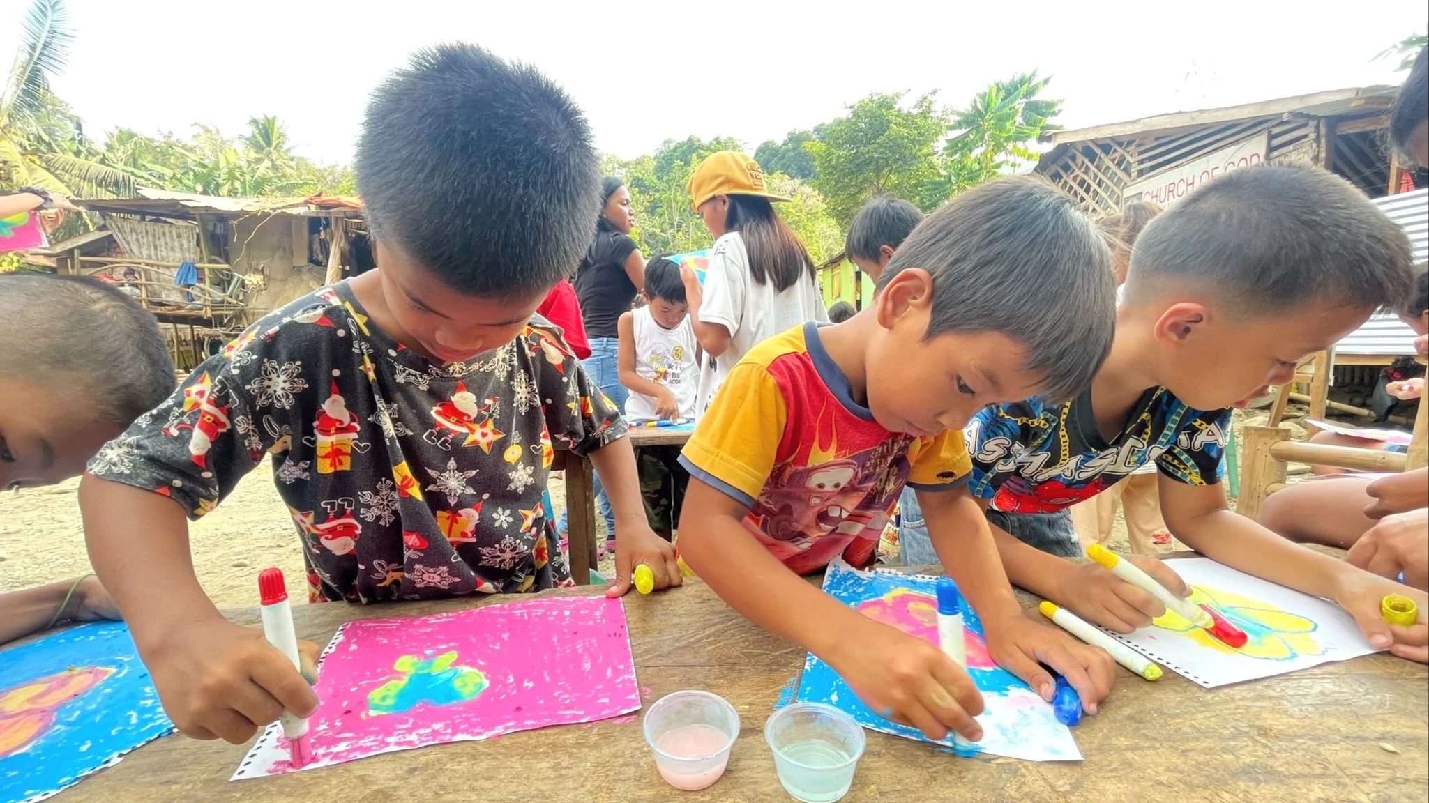 three young boys in the philippines drawing and coloring