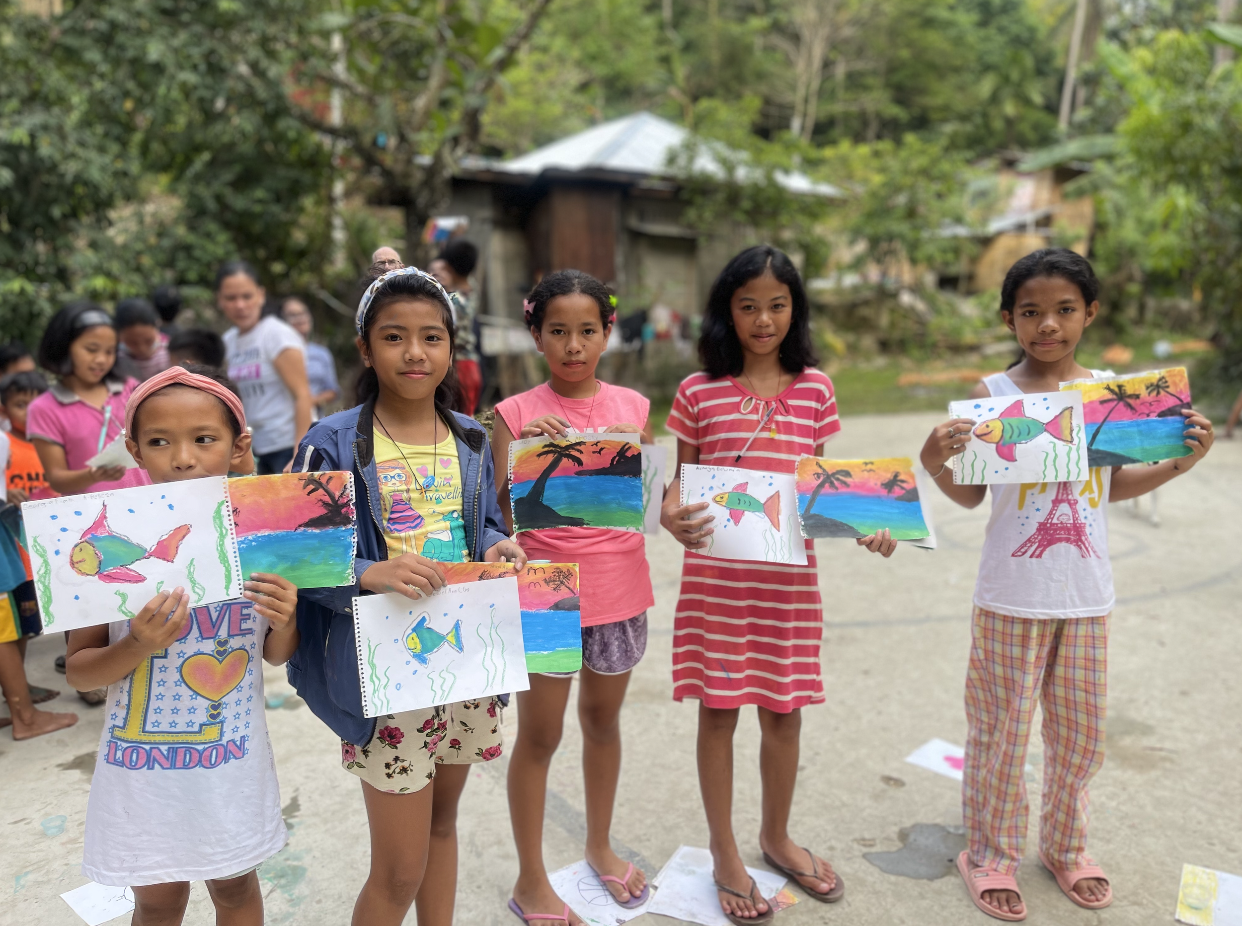 a group of girls in the philippines standing with their artwork in front of them