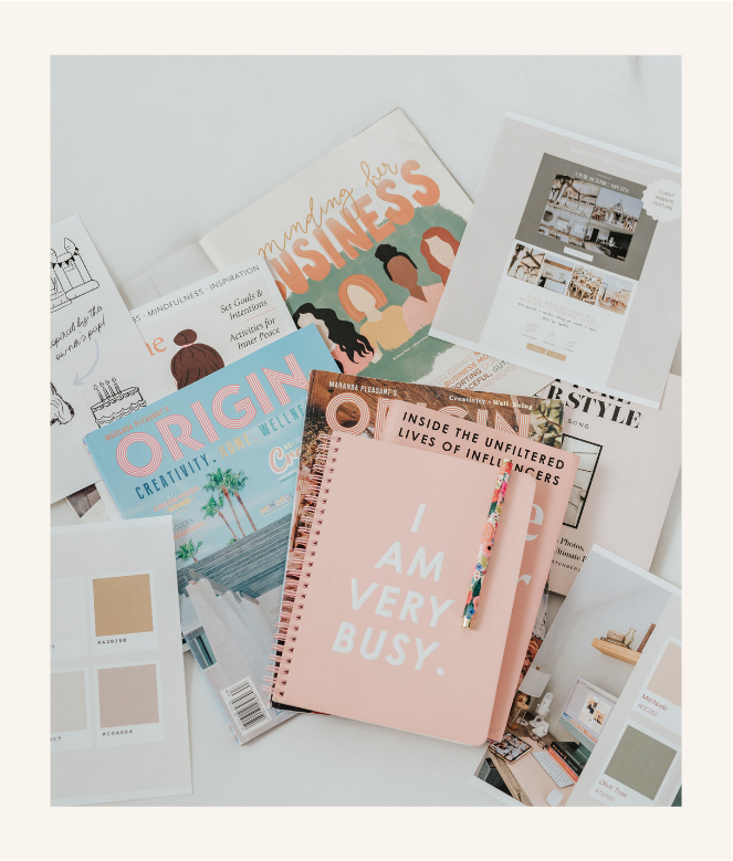 Flat lay of branding materials including magazines, color swatches, printed design mockups, and a pink notebook that says “I Am Very Busy.”