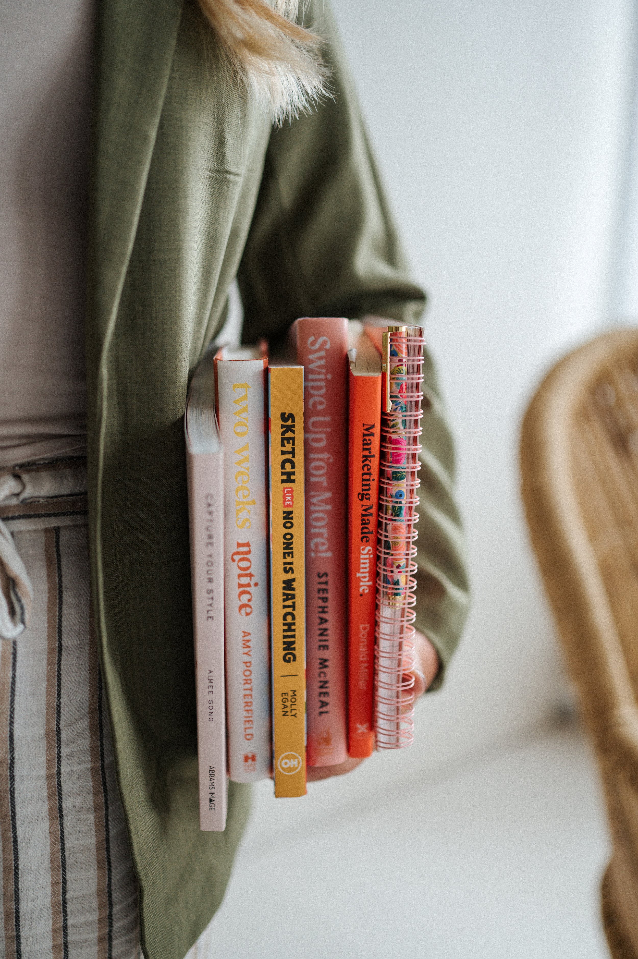 A person holding a stack of colorful books at their side