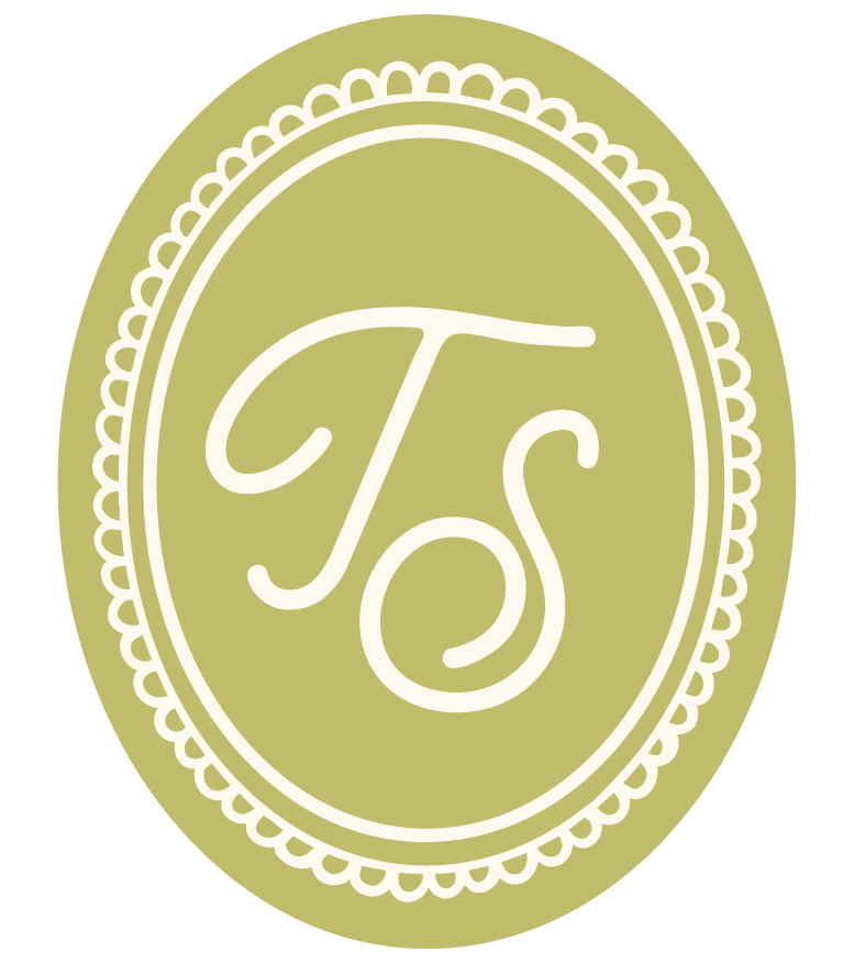 Olive green oval badge with scalloped border featuring the initials “TS” in white script.