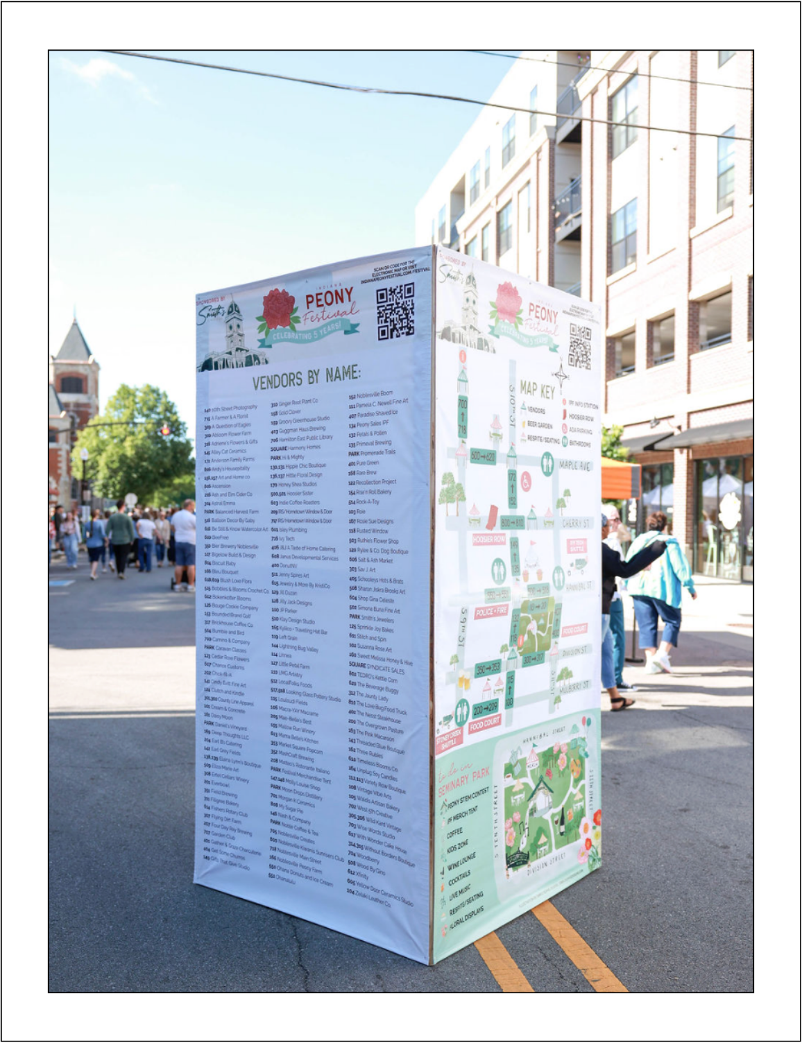 Large wayfinding cube for the Indiana Peony Festival in downtown Noblesville, Indiana featuring a vendor list, illustrated map of Seminary Park, and QR codes for the event map.