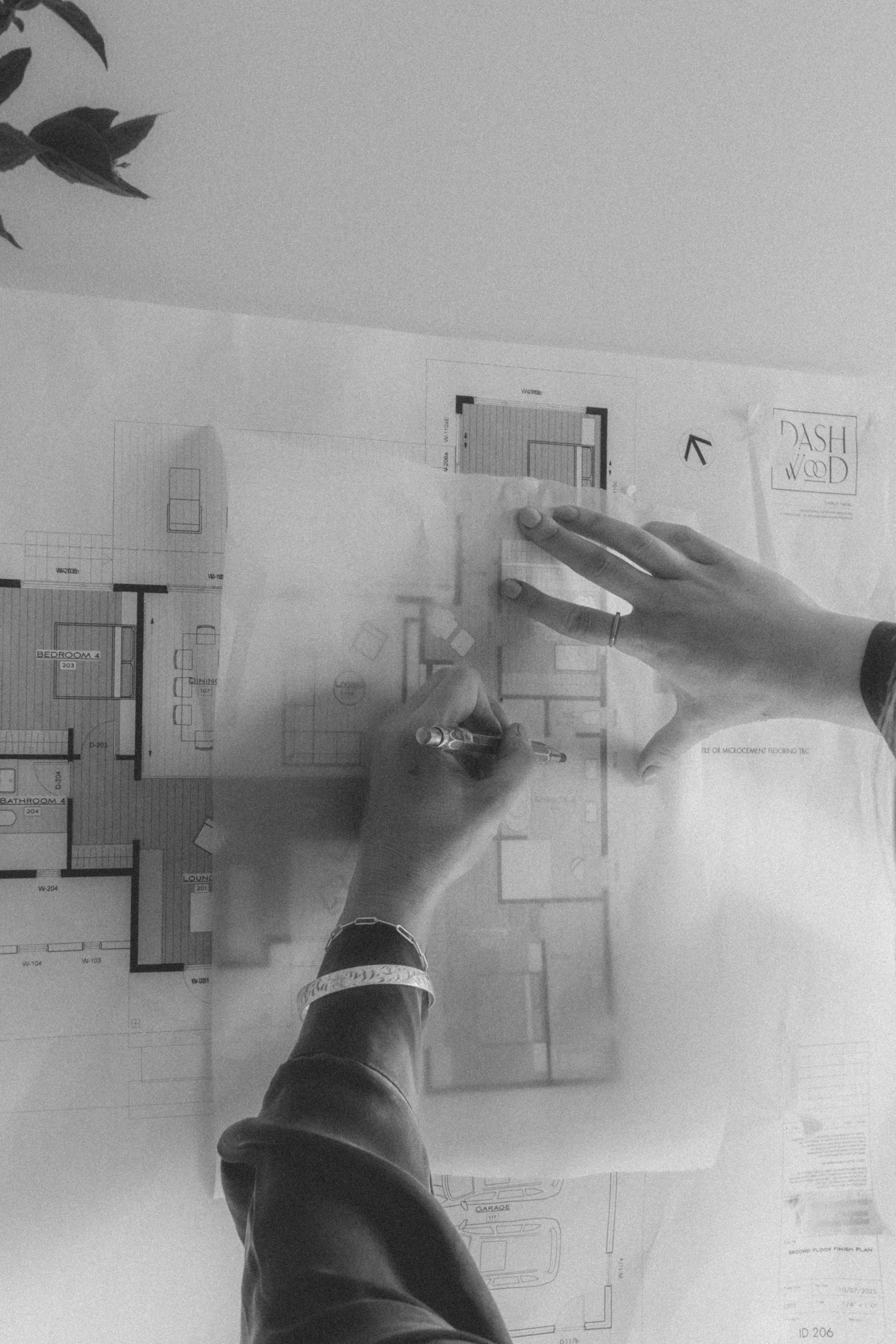 Person pointing at architectural floor plans on a desk.