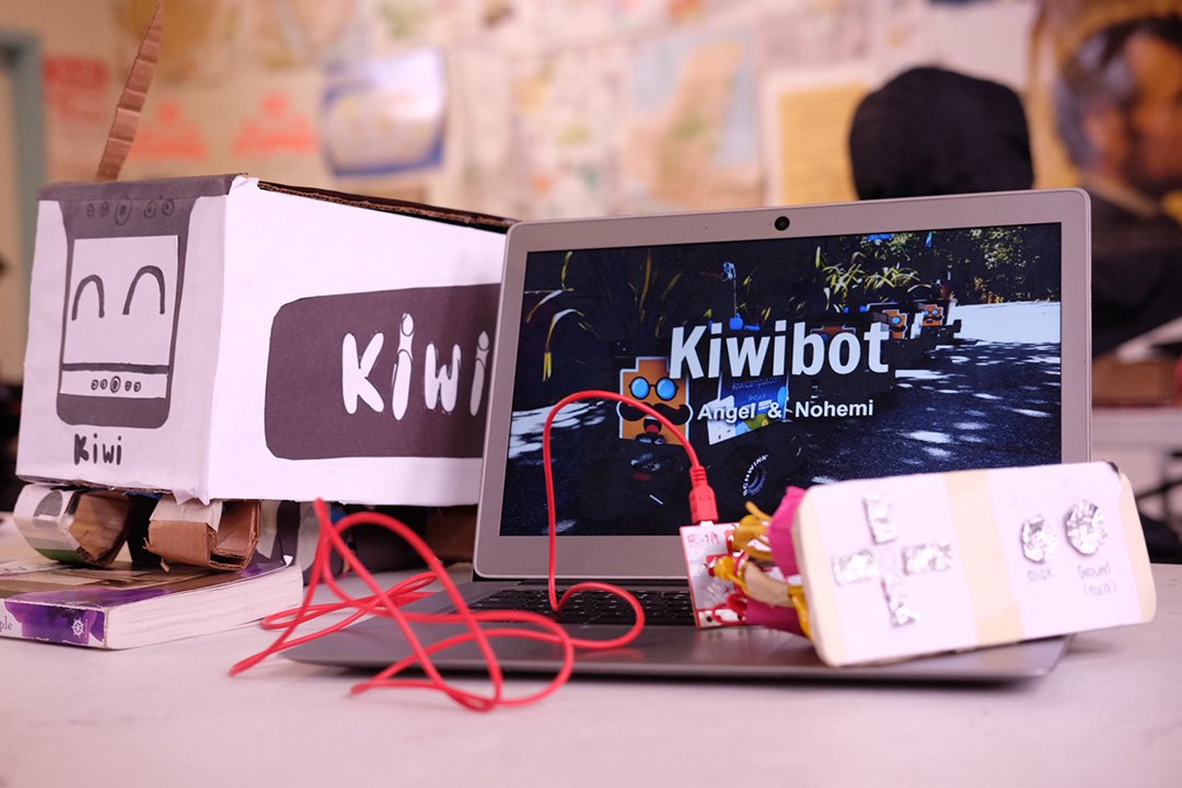 Computer science student project with a cardboard model of a robot a presentation about it on the computer with a controller attached.