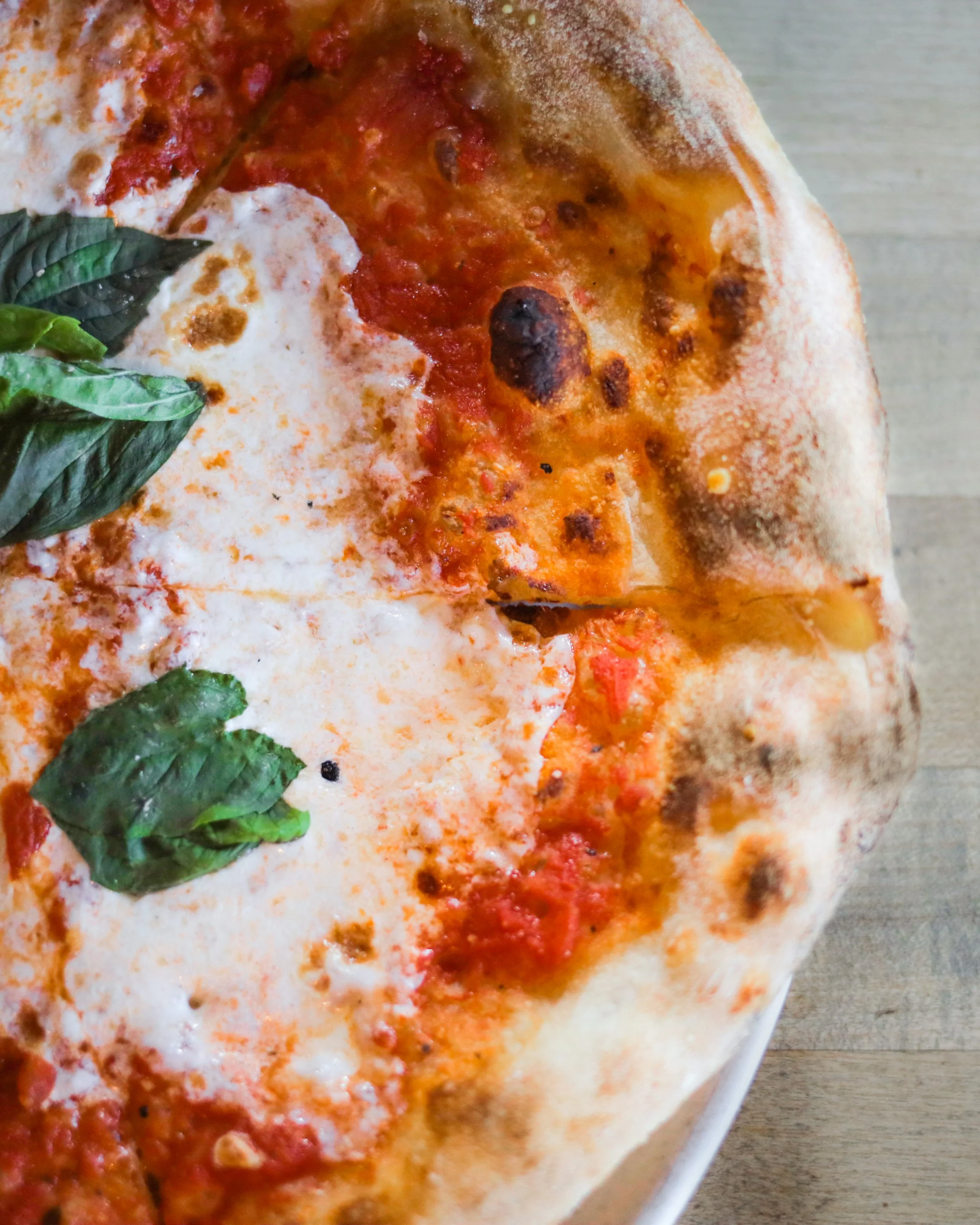 Close-up of a Margherita pizza with tomato sauce, mozzarella cheese, and fresh basil leaves on a thin, crispy crust.