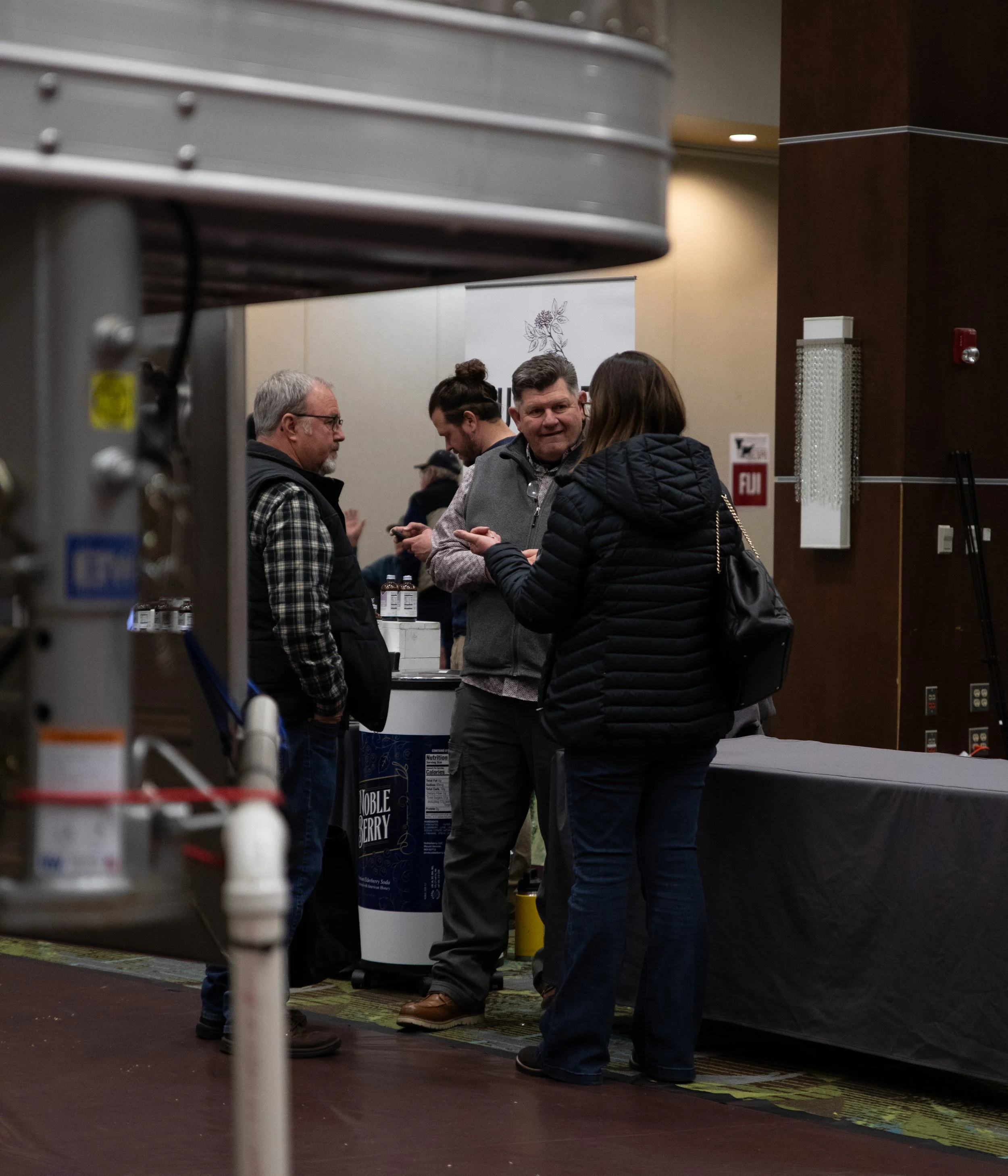 A man in a blue plaid shirt scrolls on his cell phone.