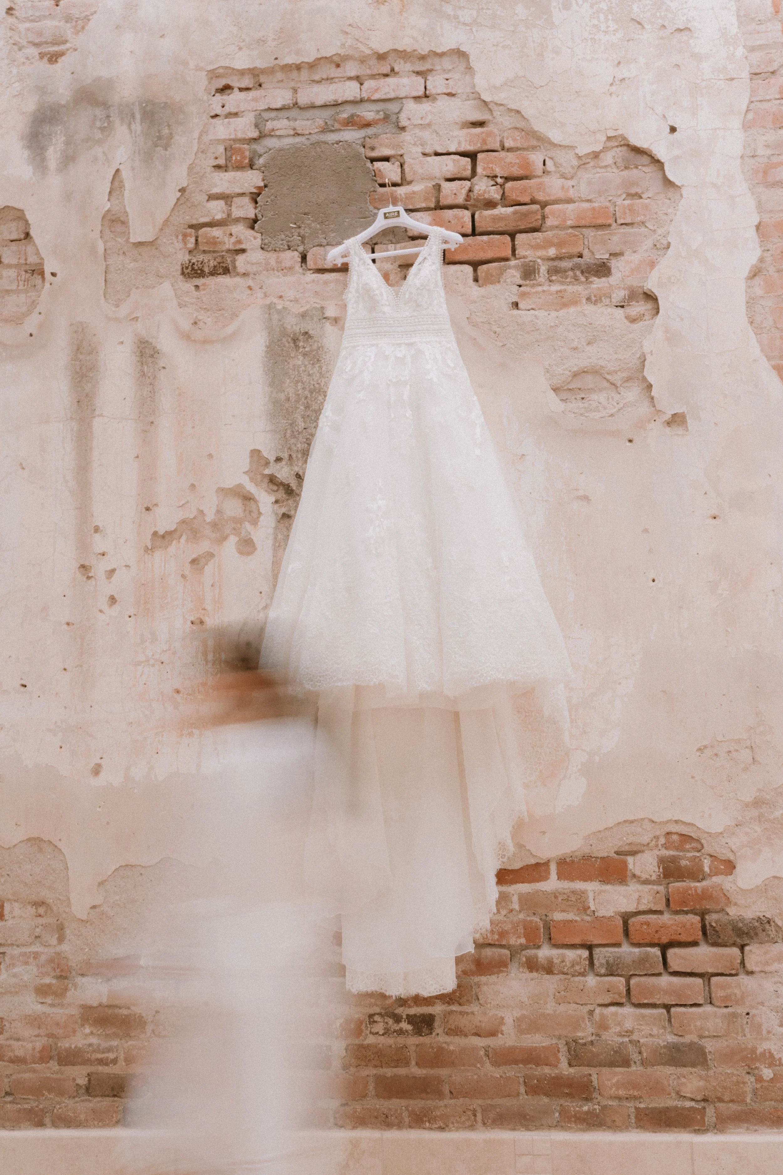 Vestido de novia blanco colgado en una pared de ladrillos y paredes desgastadas.
