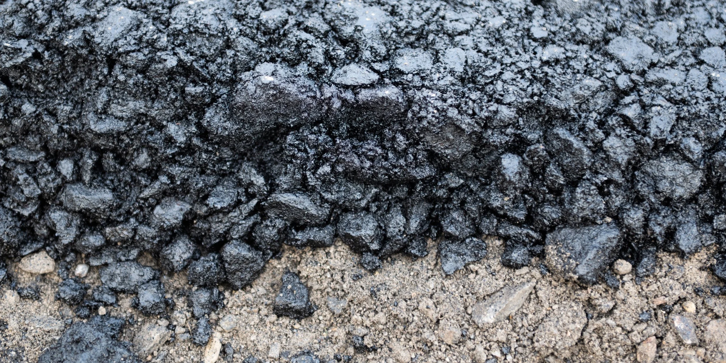 Fresh asphalt layer during the curing process, showing the thickness of the mix over the road base