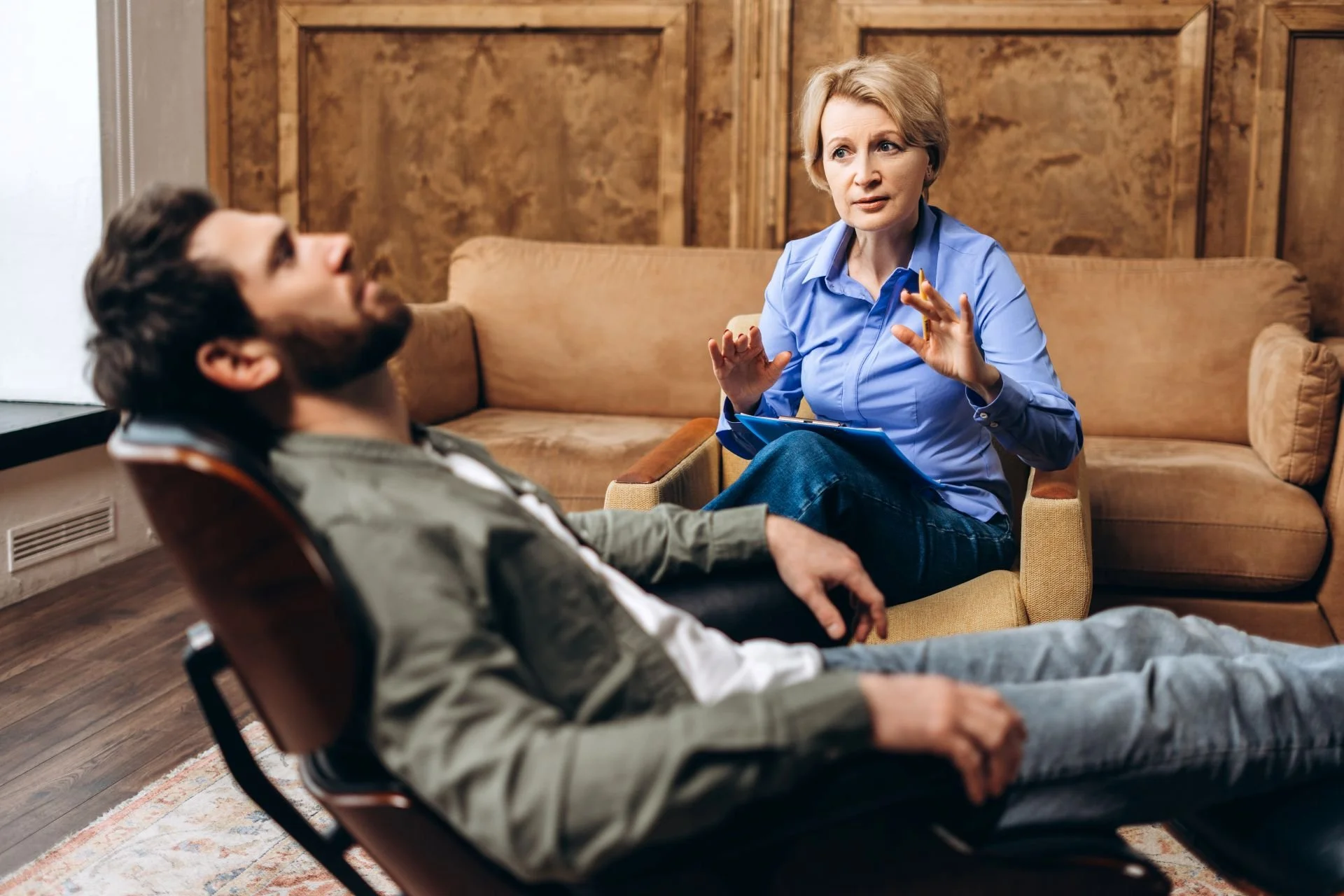 A patient lying back on a recliner chair during an EMDR therapy session with a female therapist.
