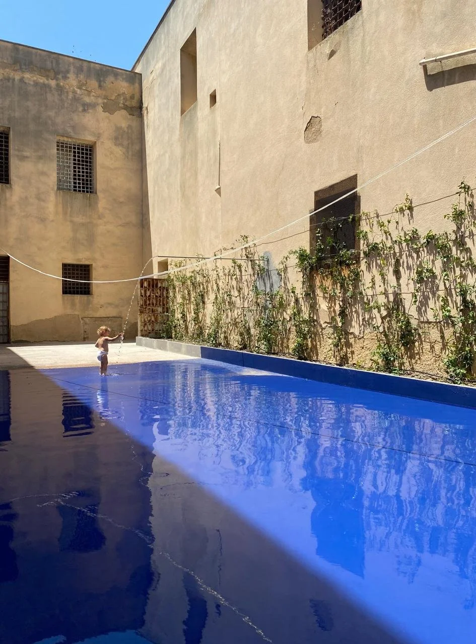 Young girl playing with water in a large public pool.