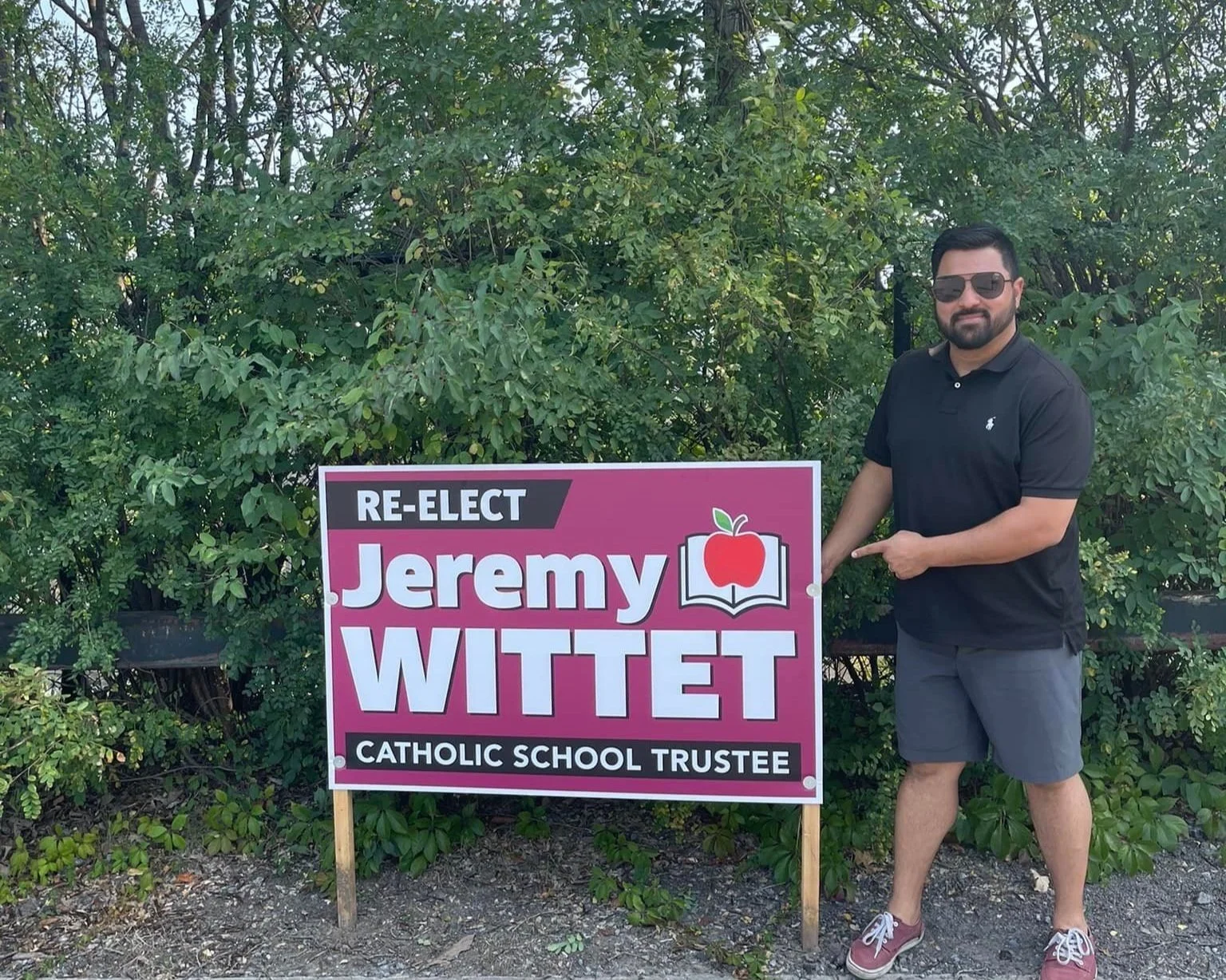 Jeremy standing by Re-elect Jeremy Wittet sign