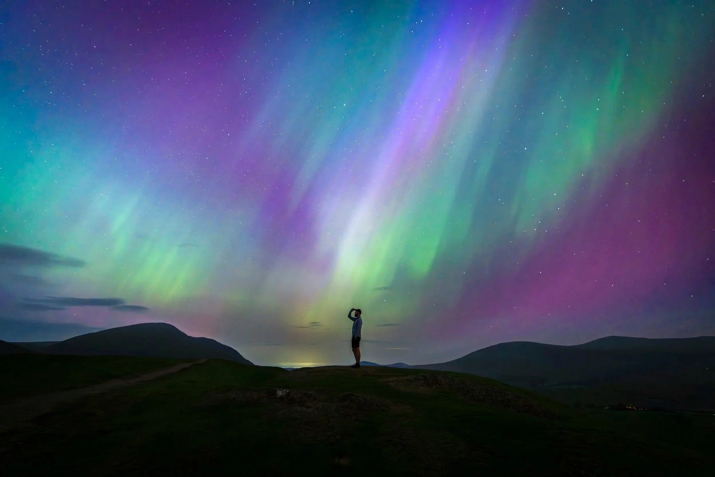 A lone figure standing beneath the northern lights