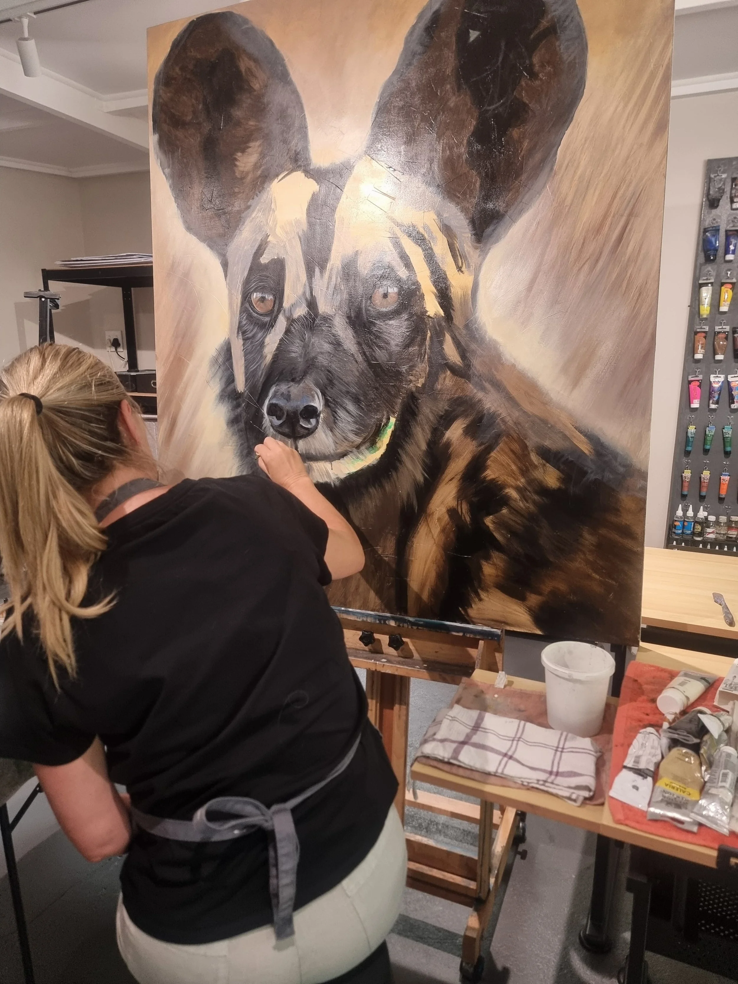 Artist painting a hyper-realistic portrait of a dog with large ears on a canvas in an art studio. Painting classes Durbanville, Adult beginner painting classes near me