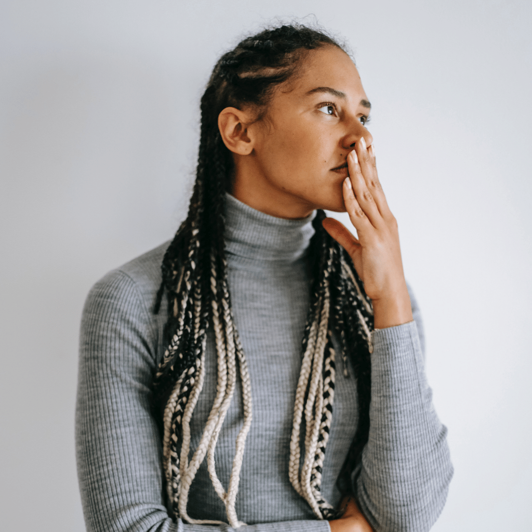 A black woman with braids staring out of a window.