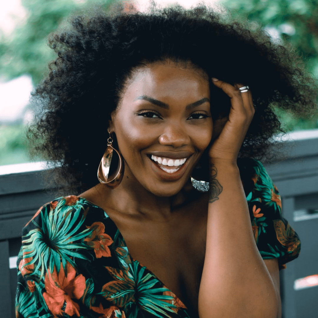 A black woman with curly hair smiling at the camera.