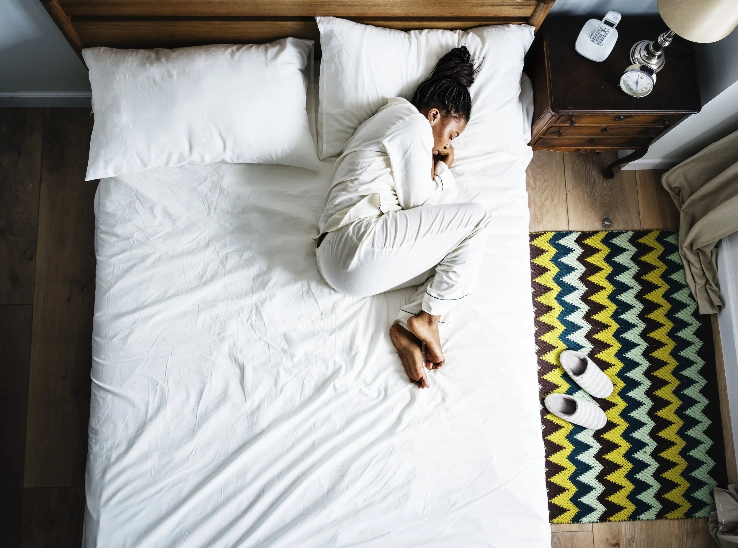 A black woman with curly hair depressed in bed.