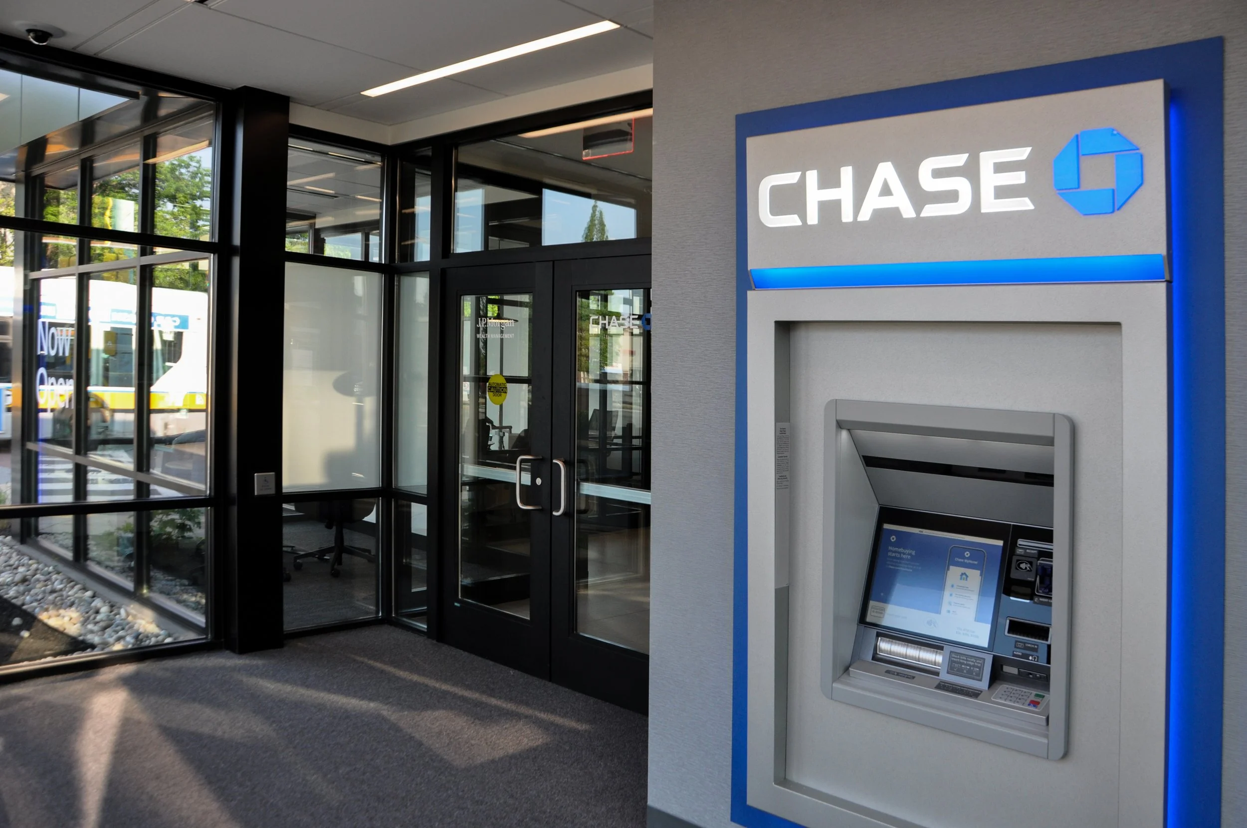 JPMC Malden vestibule with an ATM. Glass doors and store front surrounds the atrium, the ATM is built into the wall and has Chase's logo on top of it.