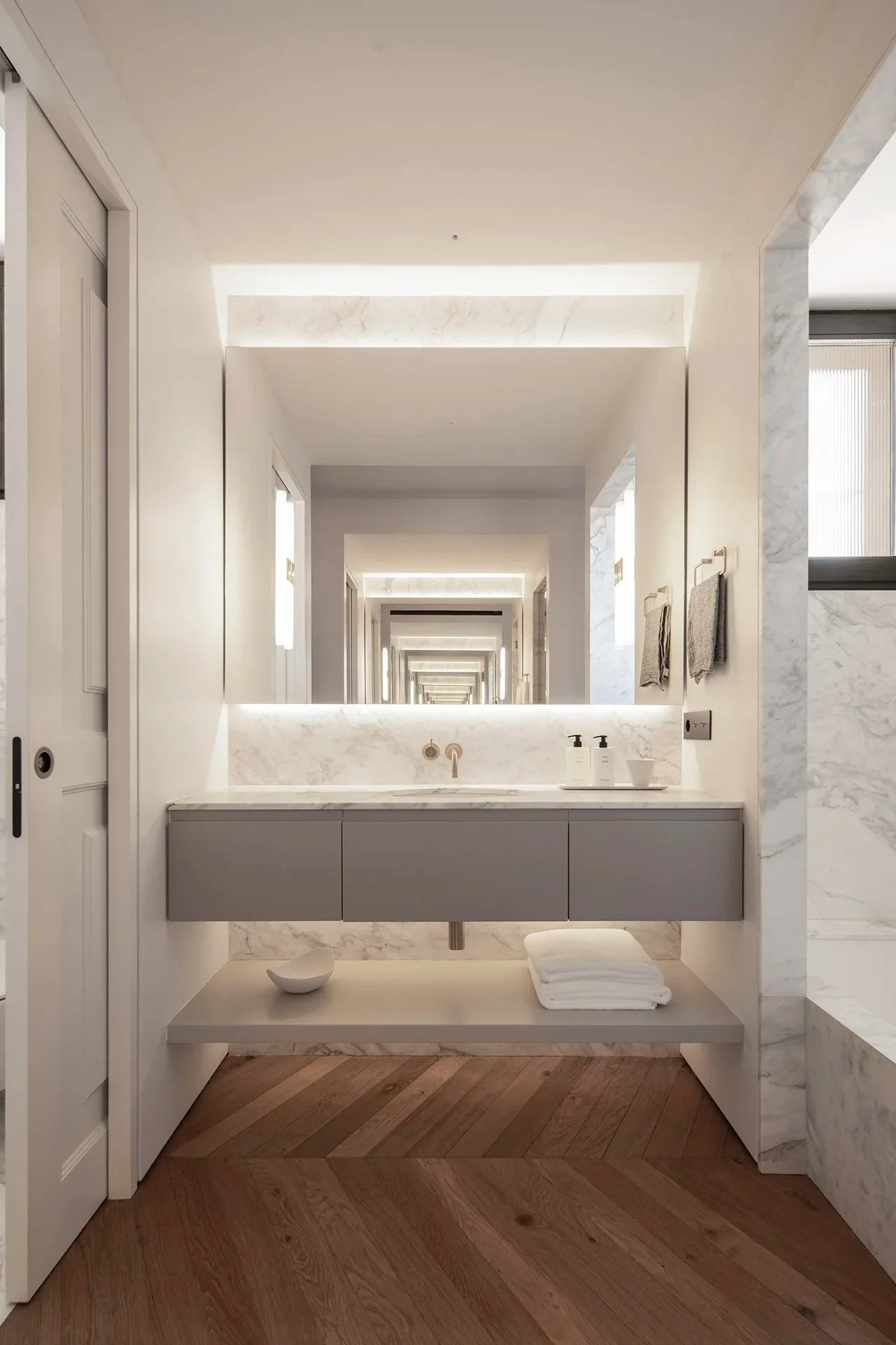 Double vanity with illuminated mirrors and marble walls in the owner’s bathroom