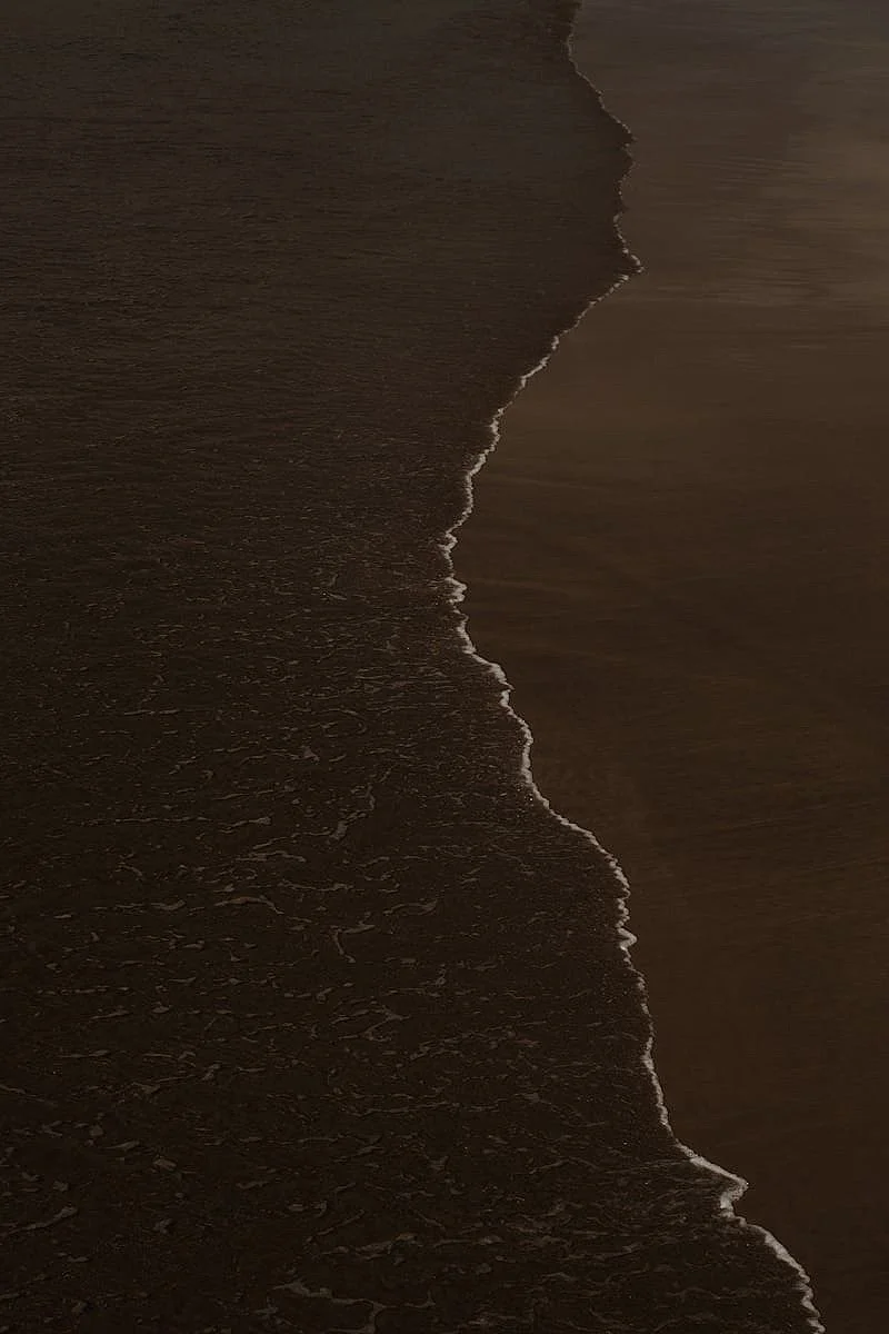 Aerial view of ocean waves breaking onto a sandy beach during sunset or sunrise.