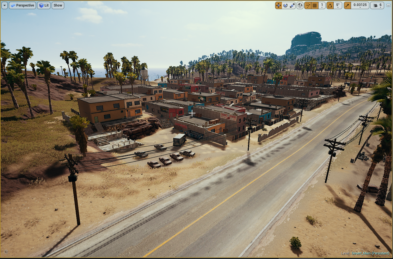 A desert town with small buildings, palm trees, a large road, and parked cars. In the background, hills are visible under a partly cloudy sky.
