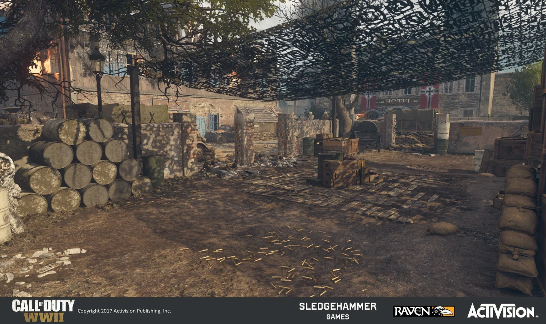 A war-torn outdoor setting with barrels, crates, sandbags, and debris, with burnt trees and damaged buildings in the background, part of a scene from Call of Duty WWII.