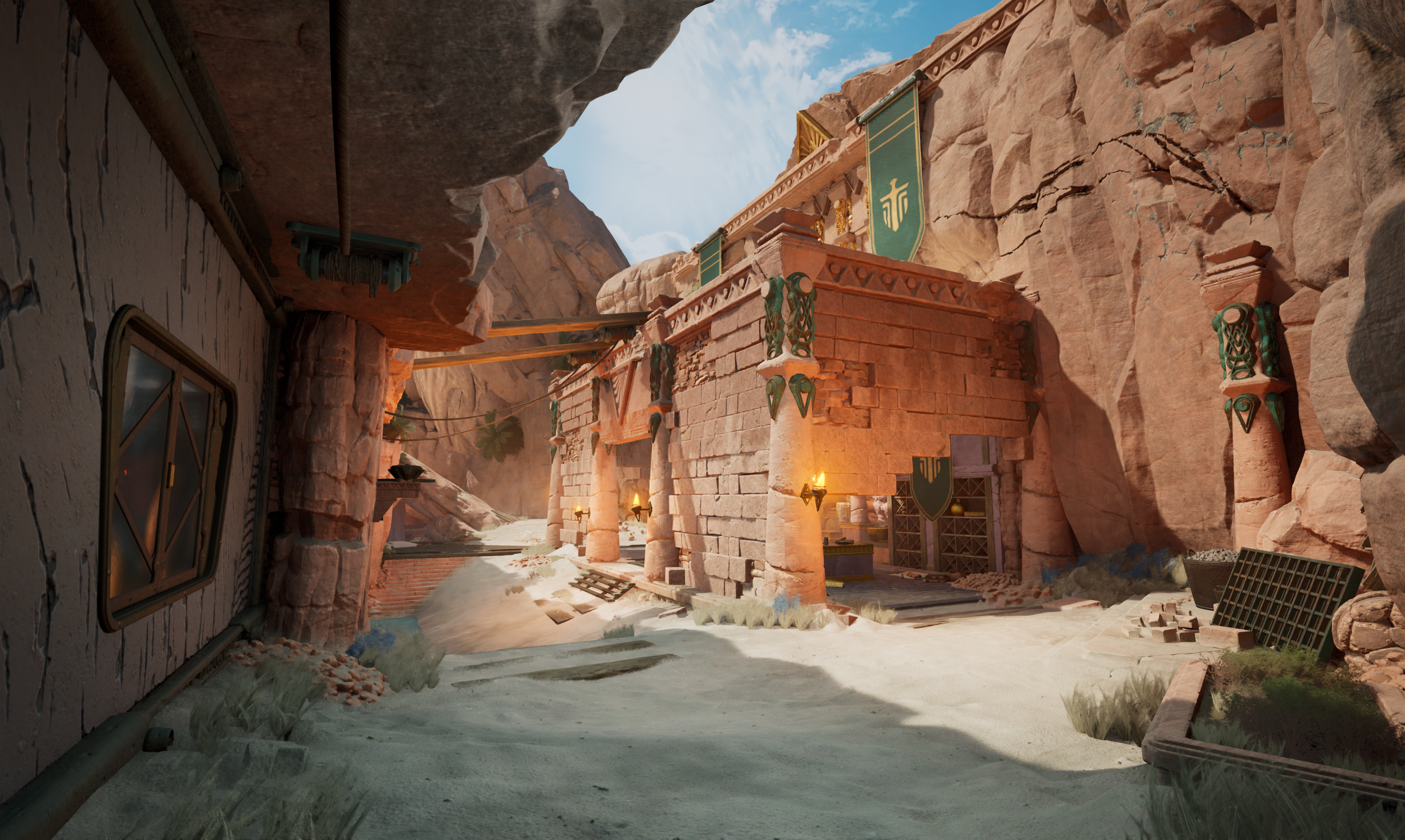 Desert canyon scene featuring a building with stone columns, banners, and torches, with rocky walls and sandy ground.