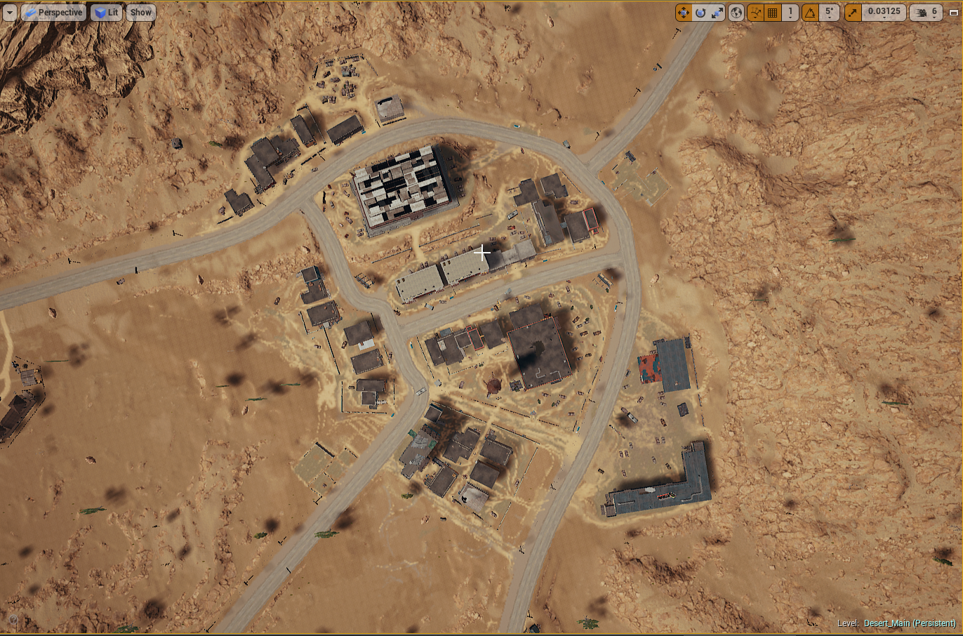 Aerial view of a desert landscape with buildings, roads, and mountains surrounding a small town.