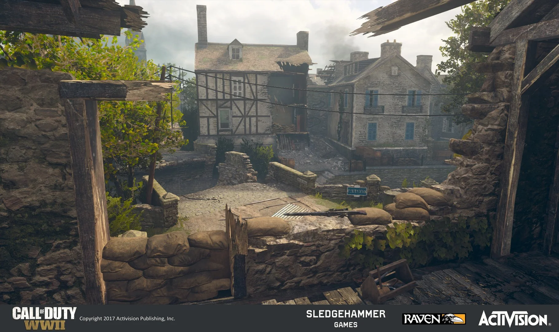 A war-torn street scene from Call of Duty WWII, showing a destroyed brick and stone building with sandbags and rubble on the street in the foreground, and damaged, partially burned houses in the background under a cloudy sky.