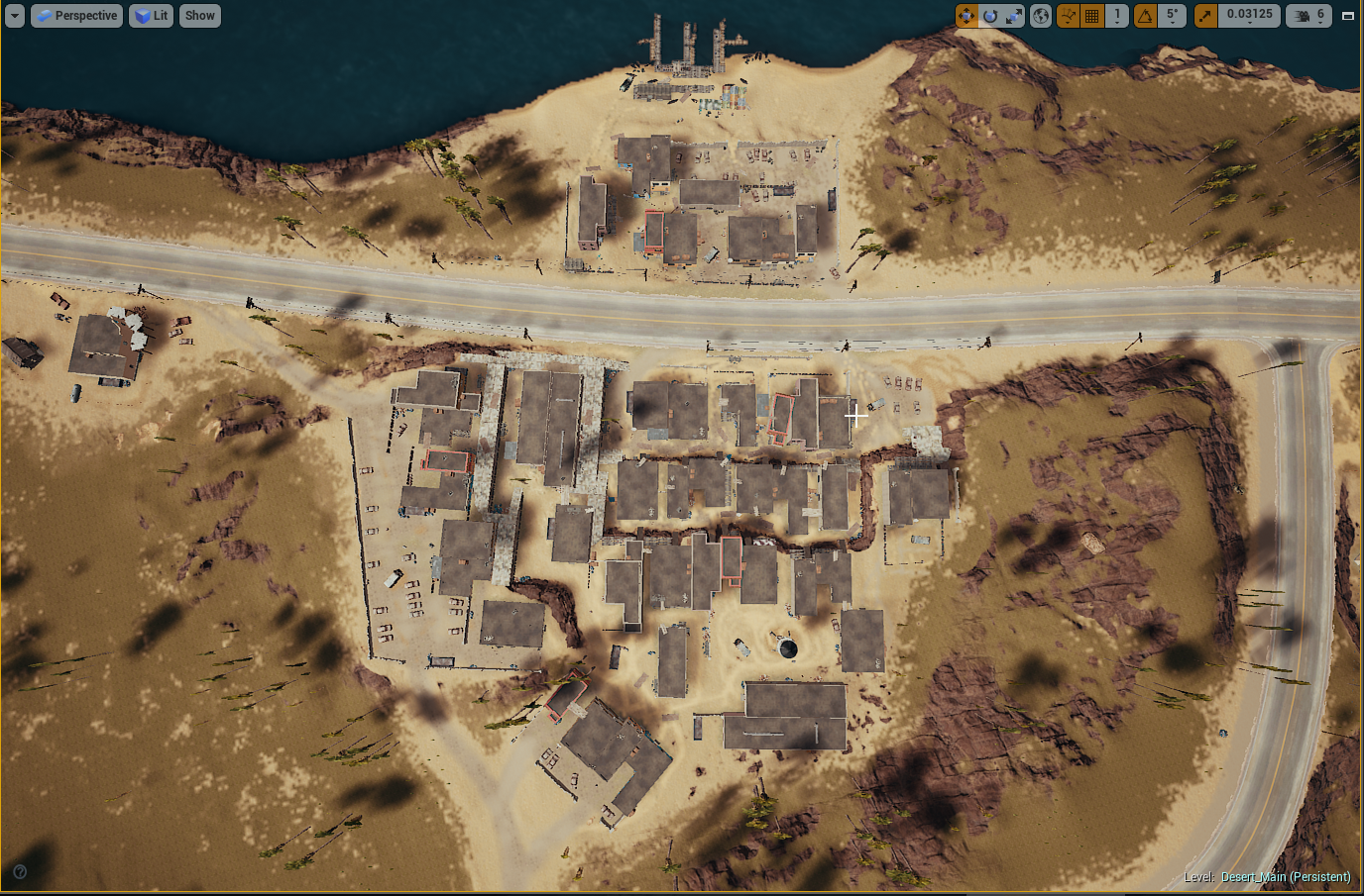 Aerial view of a desert landscape with buildings, roads, and a coastline, showing a small settlement with smoke coming from some buildings.