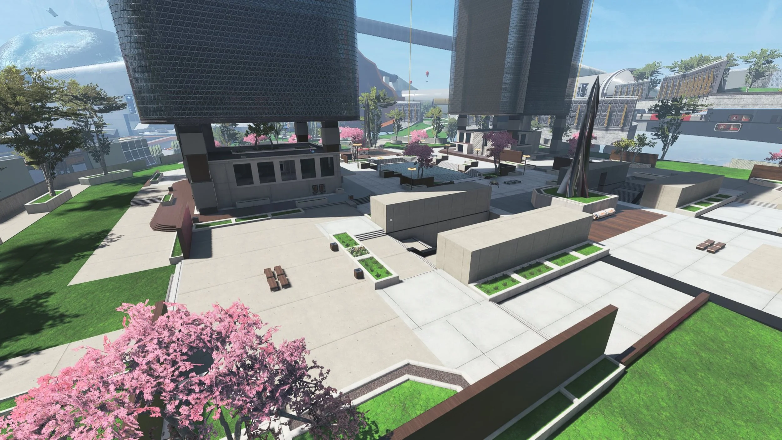 A modern urban outdoor plaza with concrete walkways, green grassy areas, blooming pink cherry blossom trees, benches, and contemporary buildings with glass and metal facades, under a clear blue sky.