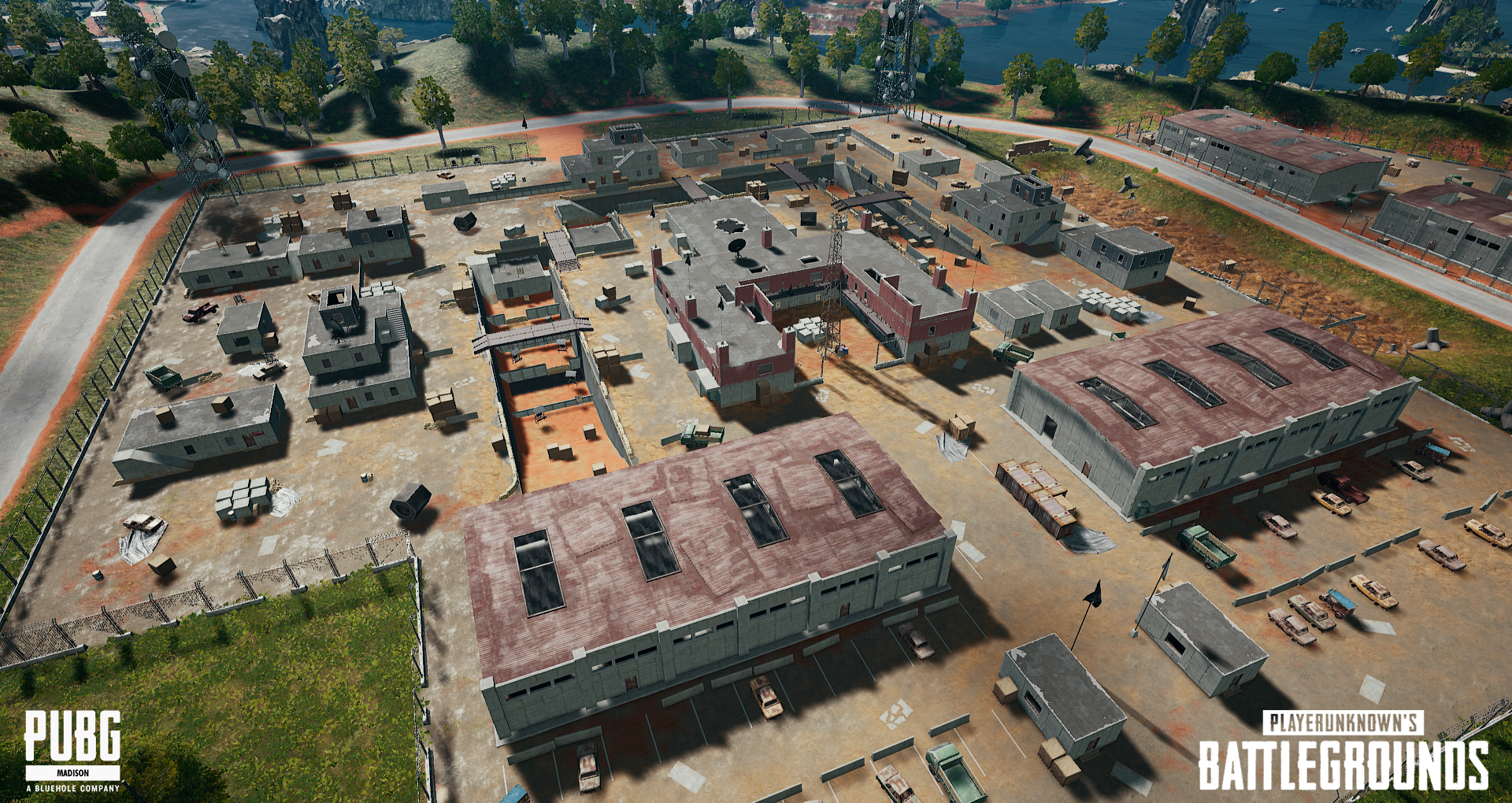 A virtual in-game map from PUBG: BATTLEGROUNDS with buildings, roads, trees, and parked vehicles, representing a game environment.