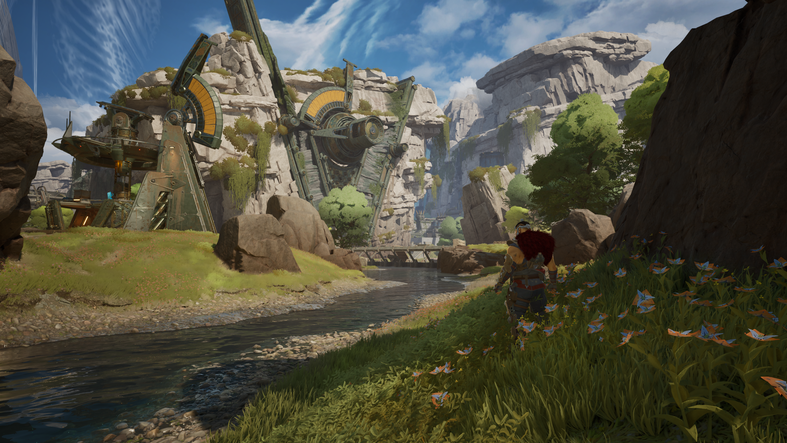 A lush green valley with a river flowing through it, surrounded by large rocks and trees. In the background, there is a futuristic structure built into the cliffs, with a clear blue sky above.