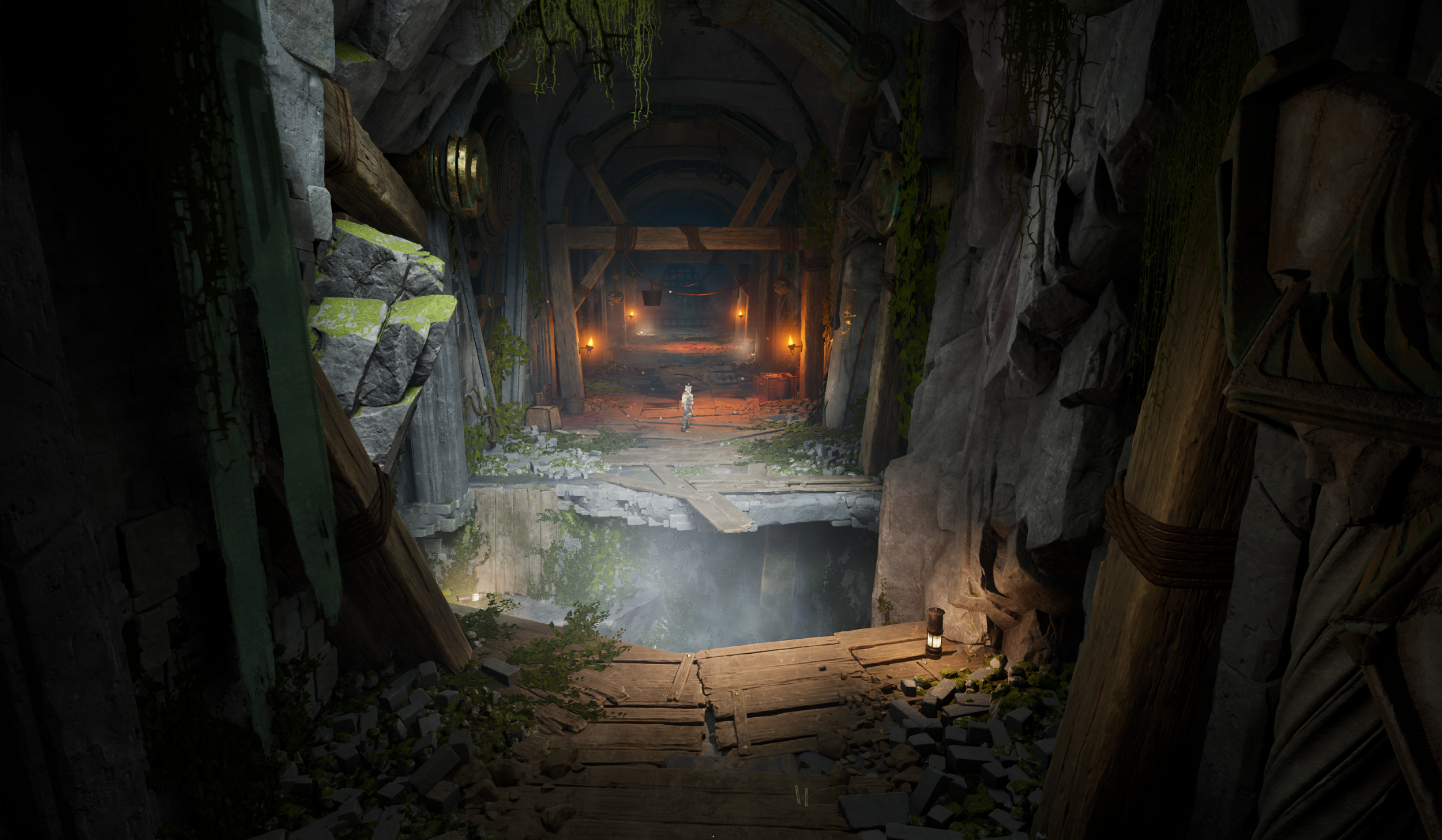 Inside an abandoned mine with a large hole in the floor and water below, wooden beams and metal pipes, moss and vines hanging from the rocky walls, lit by torches, with a figure standing in the distance.