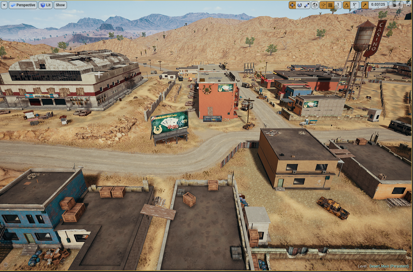 Desert town scene with buildings, a casino sign, a water tower, and mountains in the background.