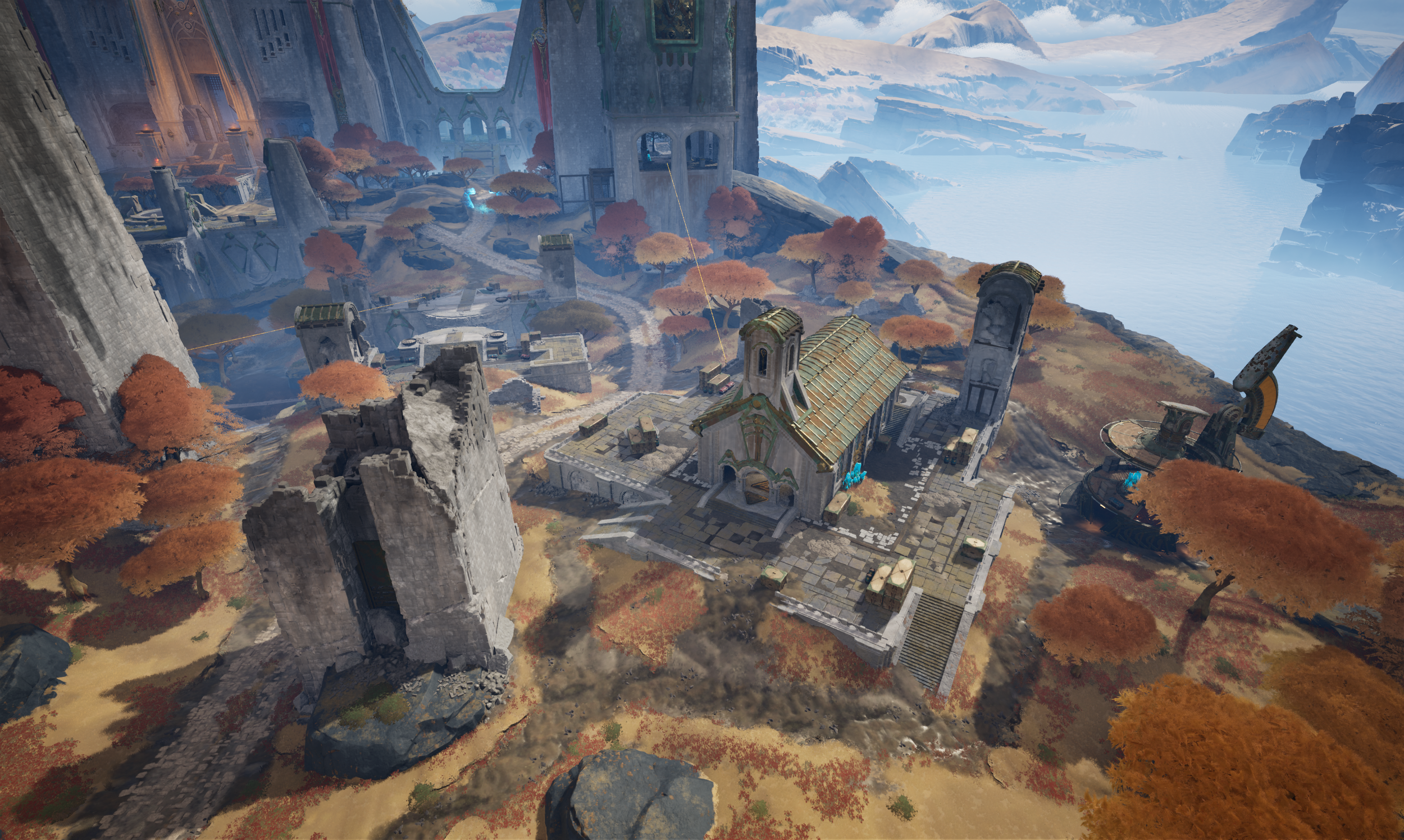 A medieval-style castle built into rocky cliffs overlooking a body of water with distant mountains. The castle has ruins, towers, and a small church with a gold roof surrounded by autumn-colored trees.