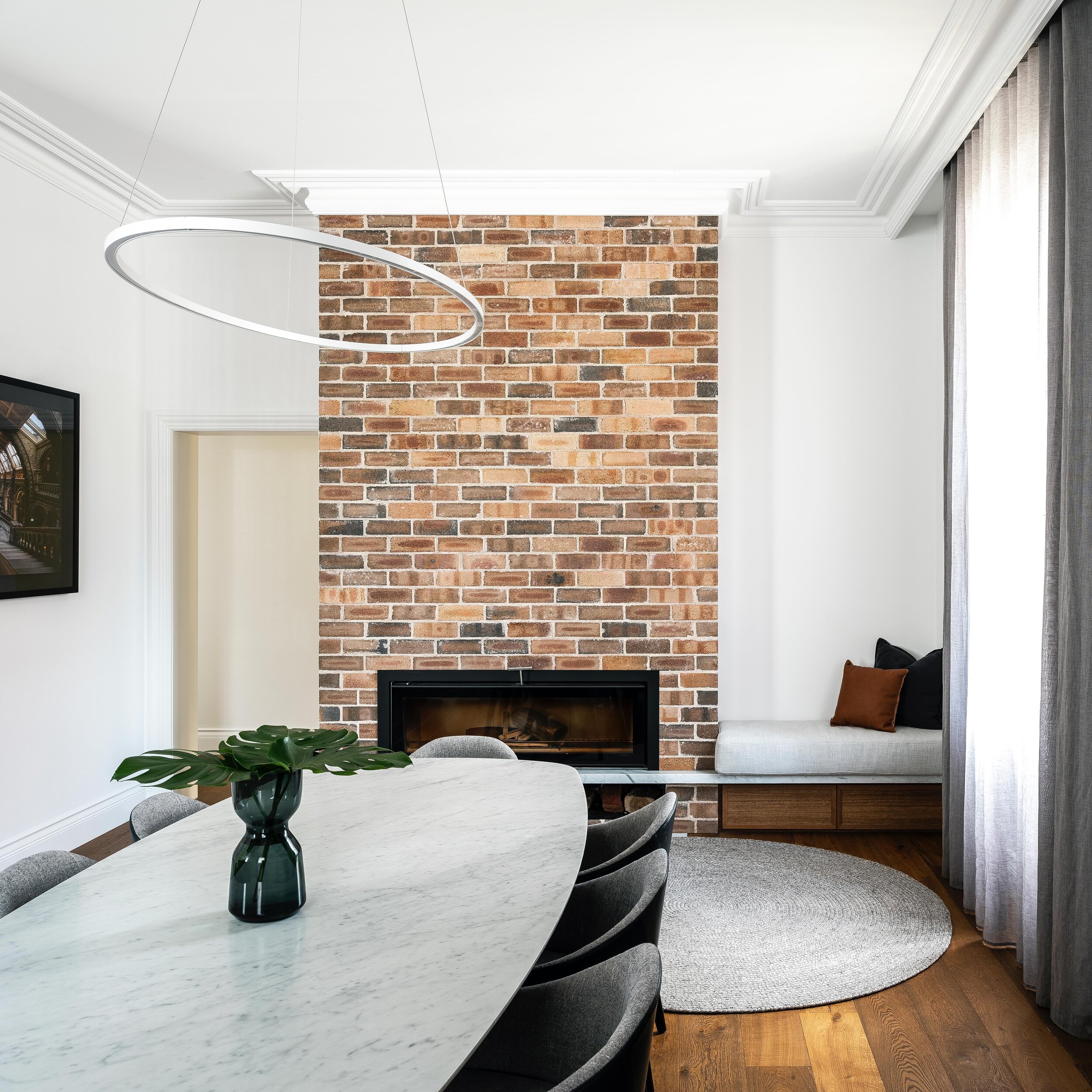 RILEY &bull; Matching the original brick was a must for the secondary fireplace within this warm living dining space. An upholstered bench seat was the perfect was to make this dining space feel conversational and flexible #InnovateInteriors