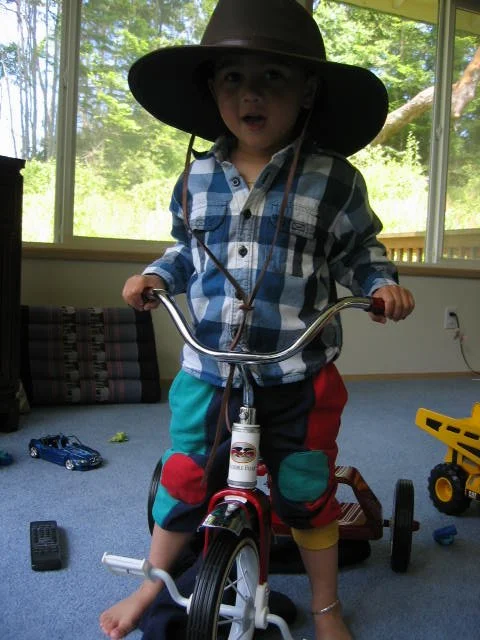 2005-6-1 COKIE ON TRIKE BEING GOOFY WITH HAT.jpg