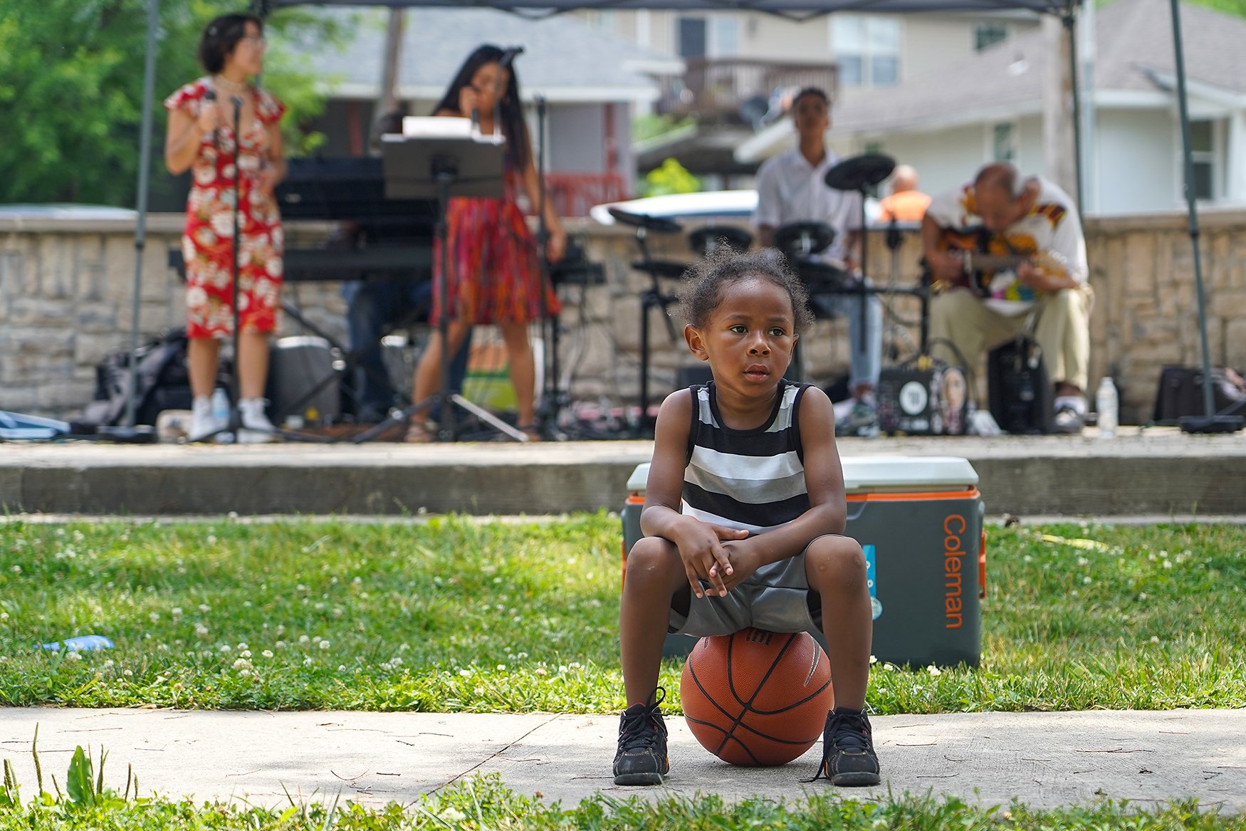 Taurell Davidson, 3, takes a break atop a basketball while the Double Helix band plays in the background at a Juneteenth celebration June 19 at Douglass Park. Taurell was given the basketball to play with by the MU basketball team, which attended the