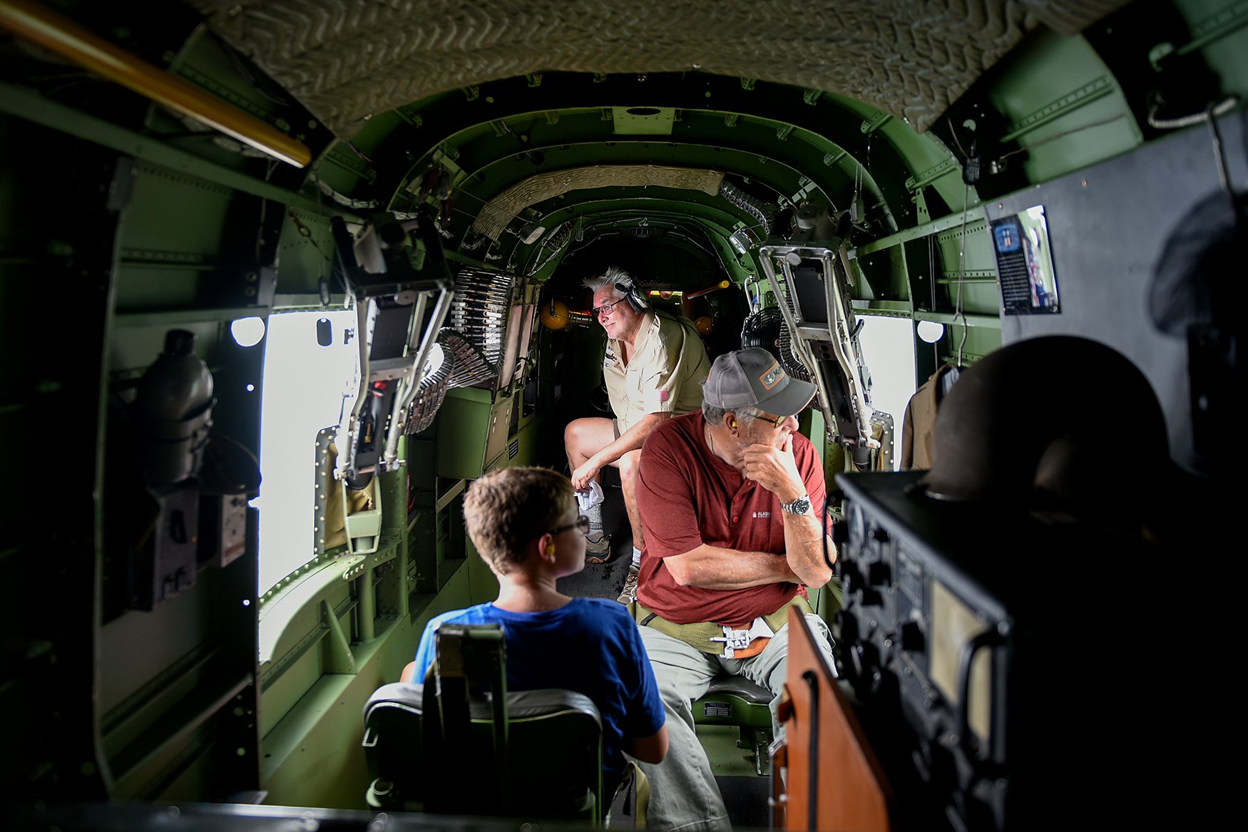 From left, Vincil Butner, 11, Paul Settle and Mark Butner gaze out the windows of a World War II-era B-25 Mitchell Bomber on July 2 at Jefferson City Memorial Airport. The inside of the bomber was decorated with World War II items including dog tags