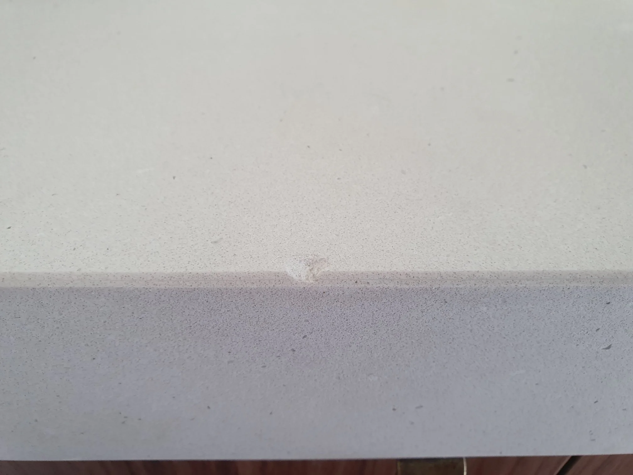 Close-up of a scratched or dented light gray surface, possibly metal or painted material.
