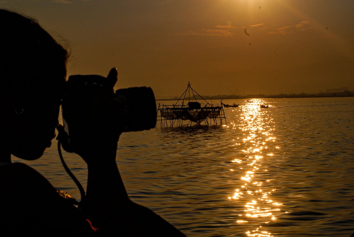 A girl takes photos as the sun sets in North Jakarta (Photo credit: The Jakarta post)