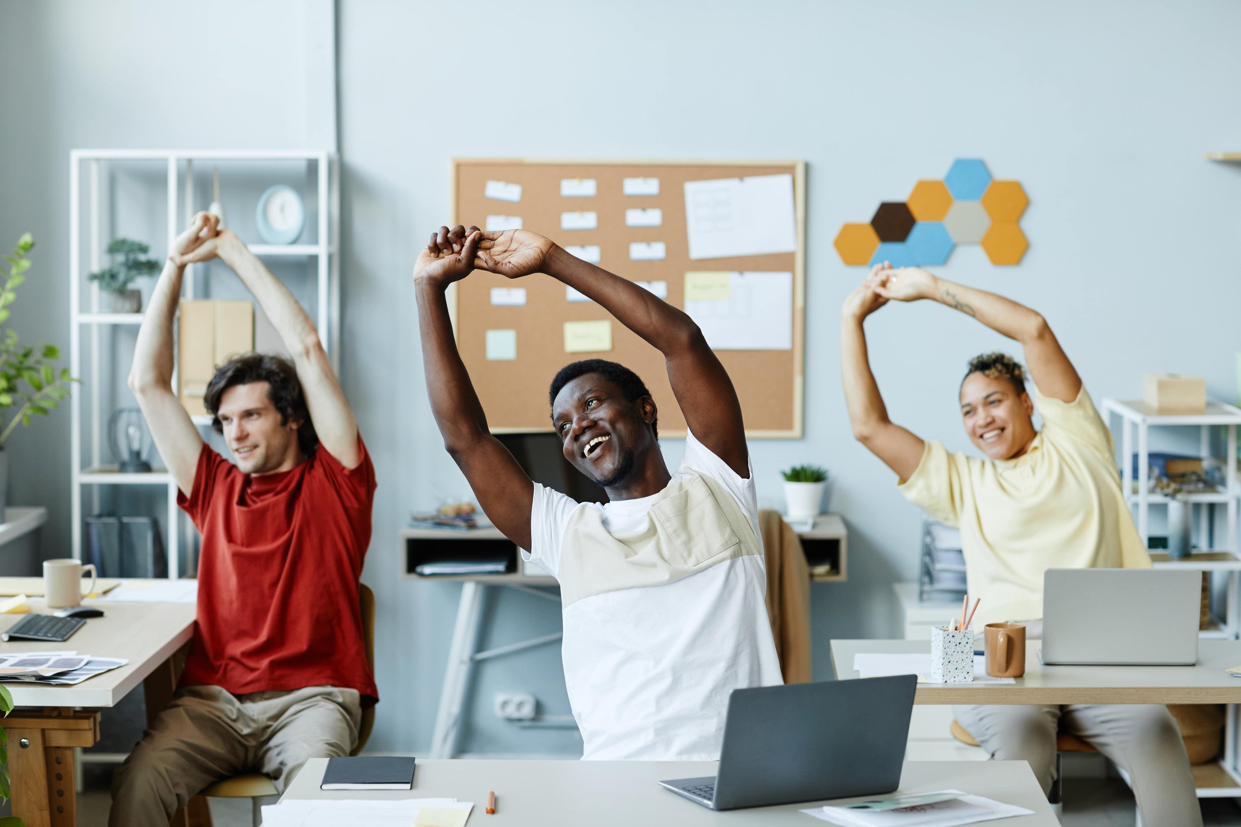 Two men and one woman stretching theirms and back at the office, sitting on a chair