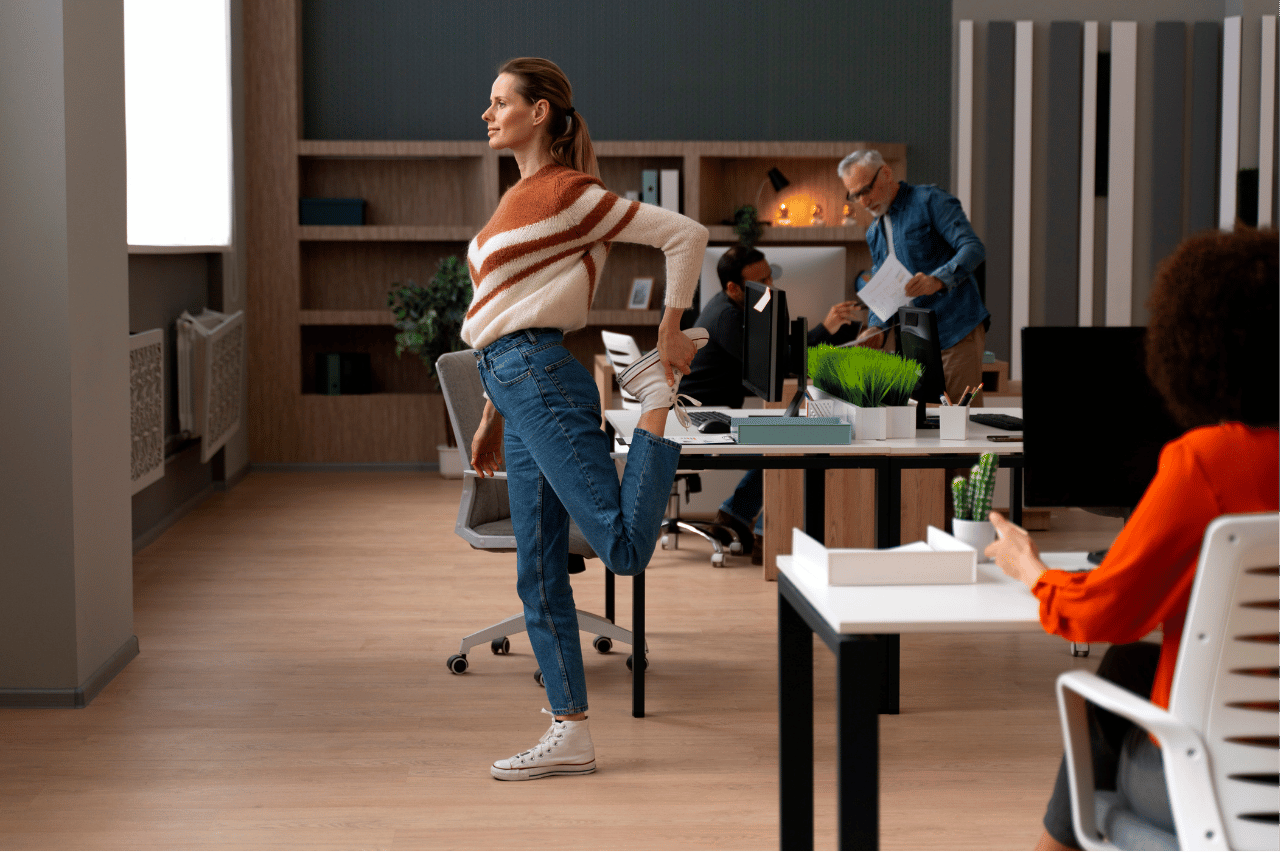 Une femme pratique une pause active debout dans les bureaux de son entreprise - Neomove