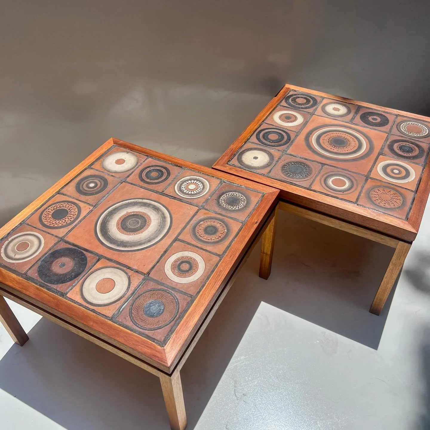Australian Blackwood side tables with hand-decorated terracotta tile tops, c.1960s&ndash;70s.

The tile designs show strong similarities to mid-century Australian studio ceramics, particularly works by Peter Travis, with their circular geometry, eart